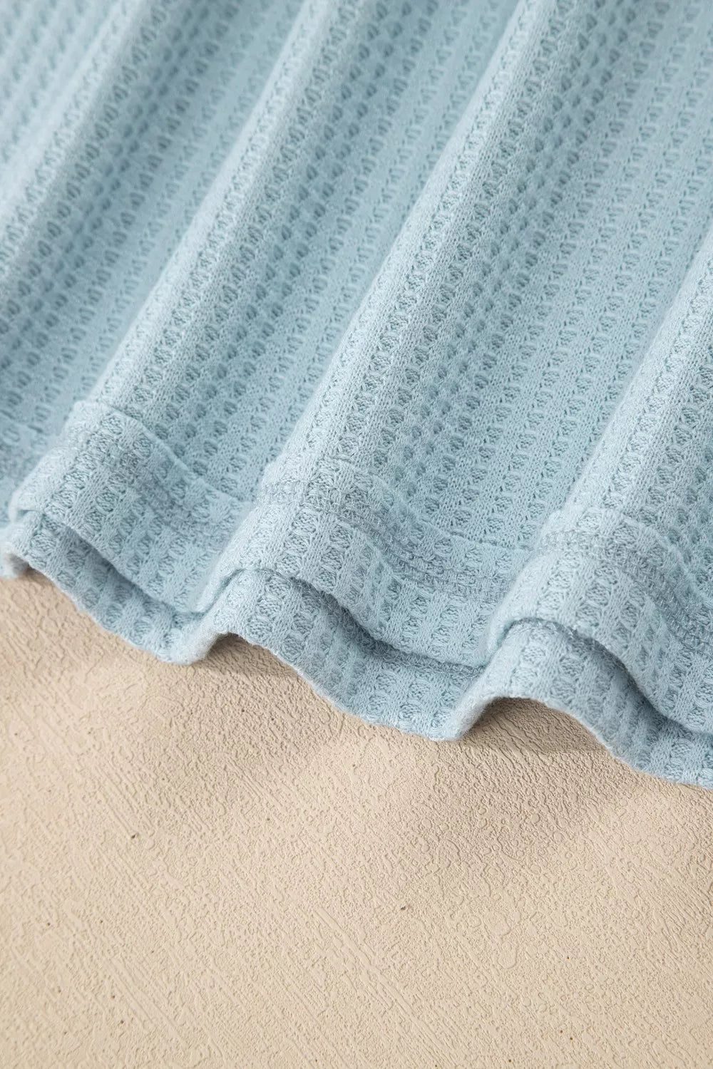soft blue waffle-knit top with floral mesh layered sleeves and relaxed feminine silhouette