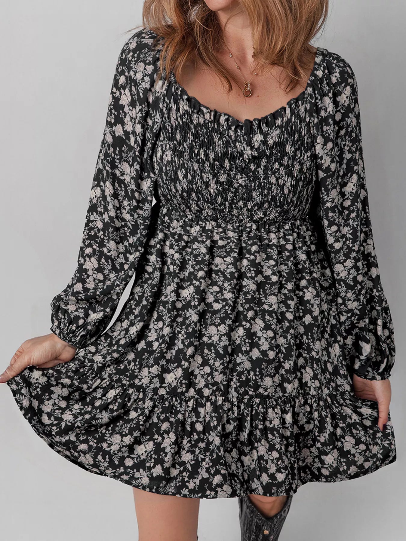 Black floral smocked mini dress with long sleeves and backless tie detail.