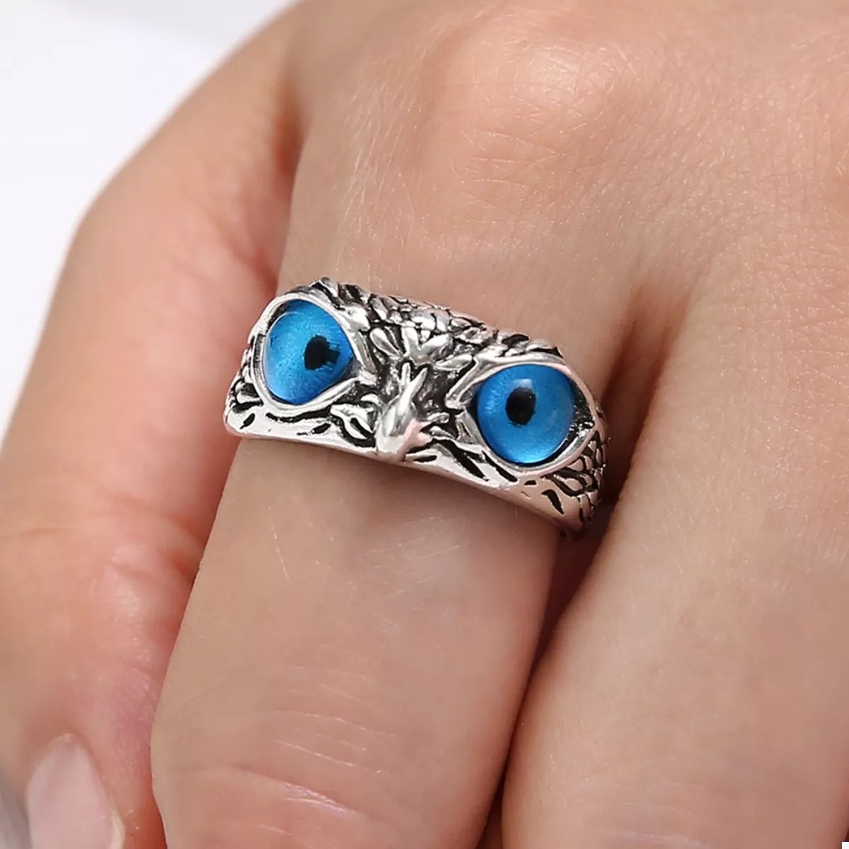 Shop the Nocturne Gaze Ring, a silver-plated alloy ring with vivid blue owl eyes. A mystical statement piece symbolizing wisdom, intuition, and protection.