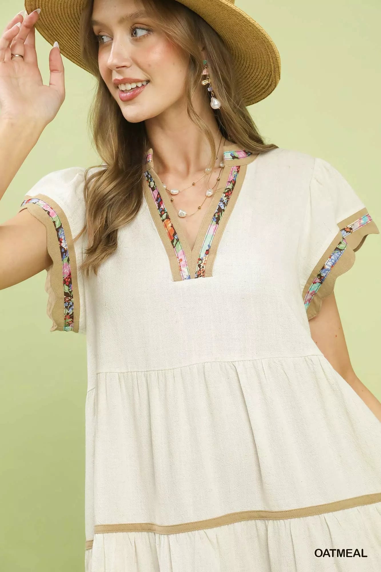 Oatmeal linen tiered mini dress with flutter sleeves, split V-neck, and colorful floral trim detailing.