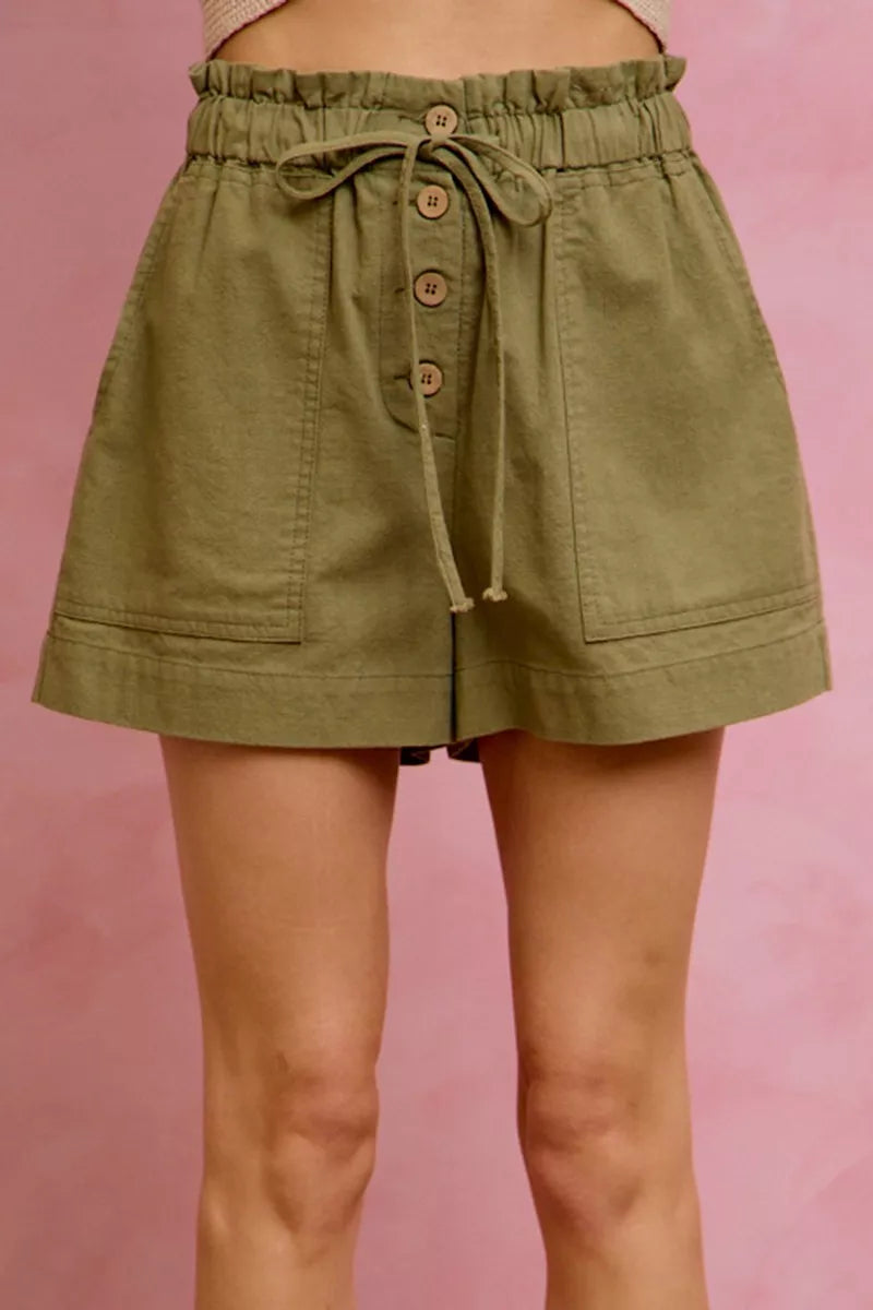 Olive green paperbag twill shorts with drawstring waist and patch pockets on model