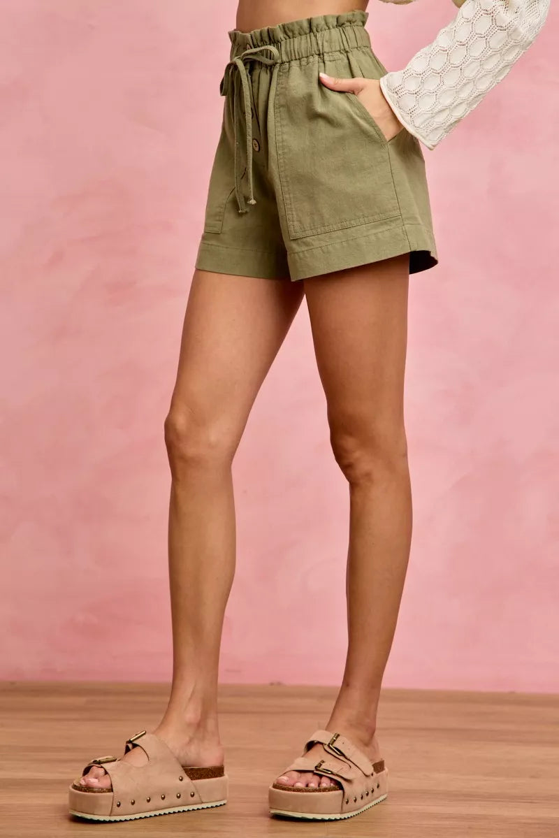 Olive green paperbag twill shorts with drawstring waist and patch pockets on model