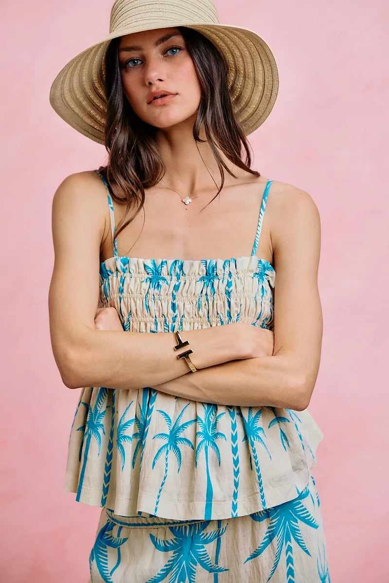 Palm print smocked cami top with adjustable straps, flowy silhouette, and tropical blue palm tree design.