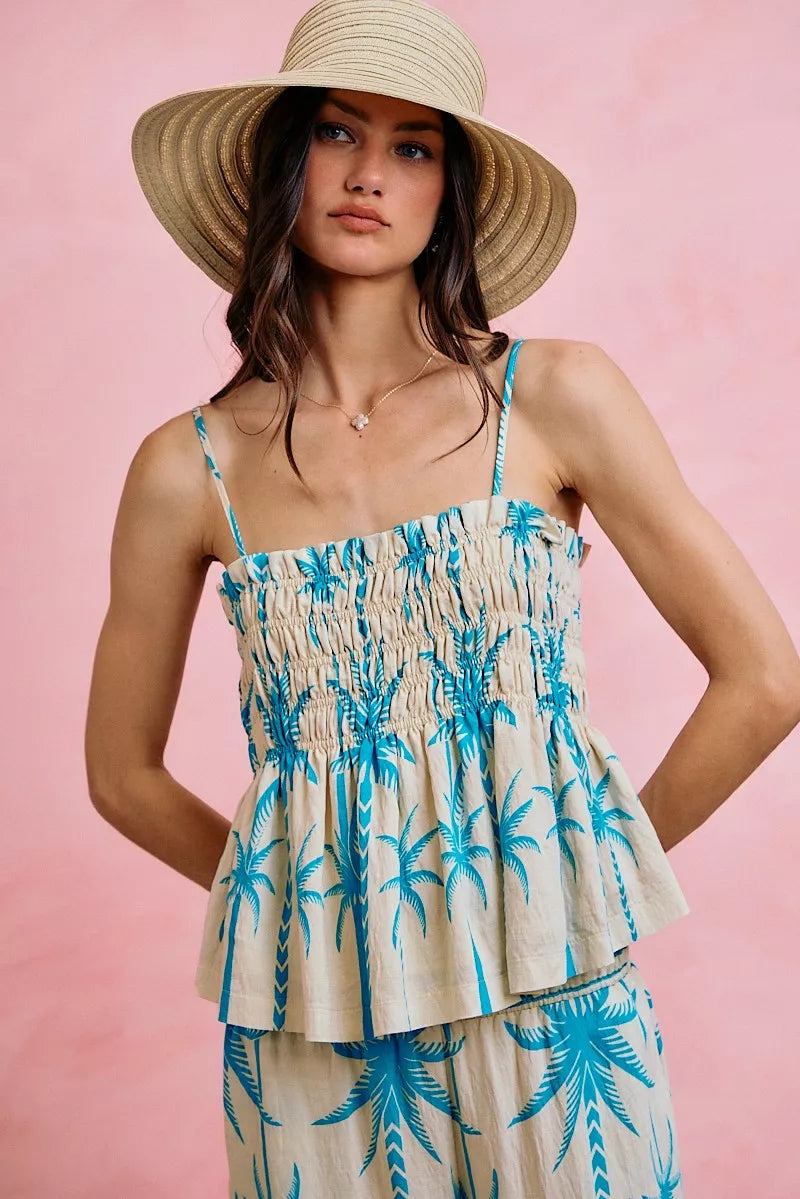 Palm print smocked cami top with adjustable straps, flowy silhouette, and tropical blue palm tree design.
