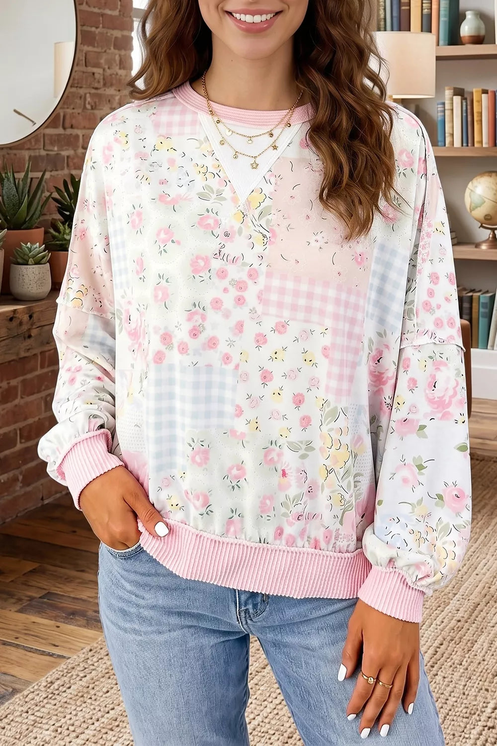 Floral patchwork pullover with soft pink ribbed trim, relaxed sweatshirt-style fit, long sleeves, and slightly stretchy fabric styled with denim.