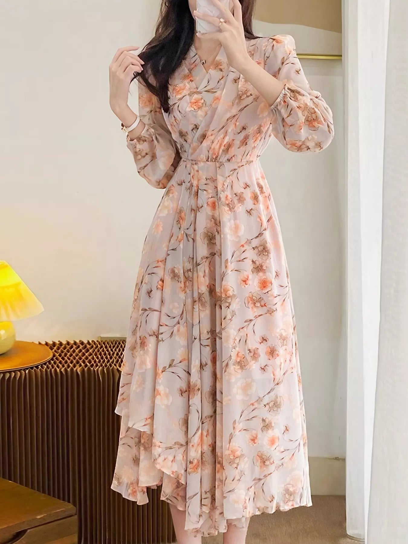 Model wearing the Peach Blossom Chiffon Midi Dress with long puff sleeves and peach floral print, styled with a white shoulder bag.
