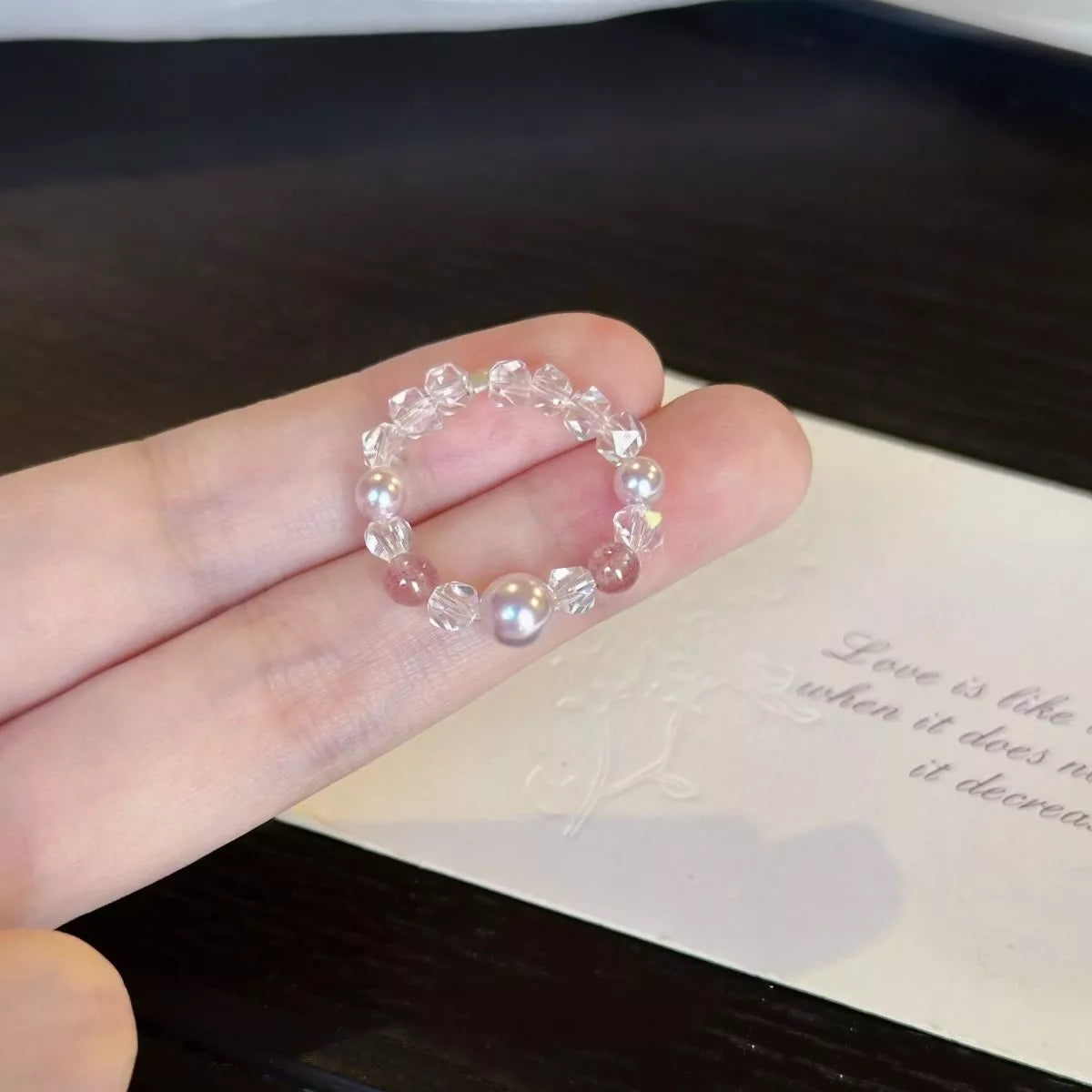 Dainty ring with a synthetic pearl accent and crystal bead details worn on a finger.