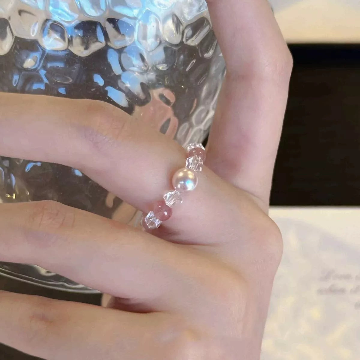 Dainty ring with a synthetic pearl accent and crystal bead details worn on a finger.