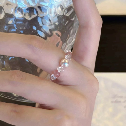 Dainty ring with a synthetic pearl accent and crystal bead details worn on a finger.