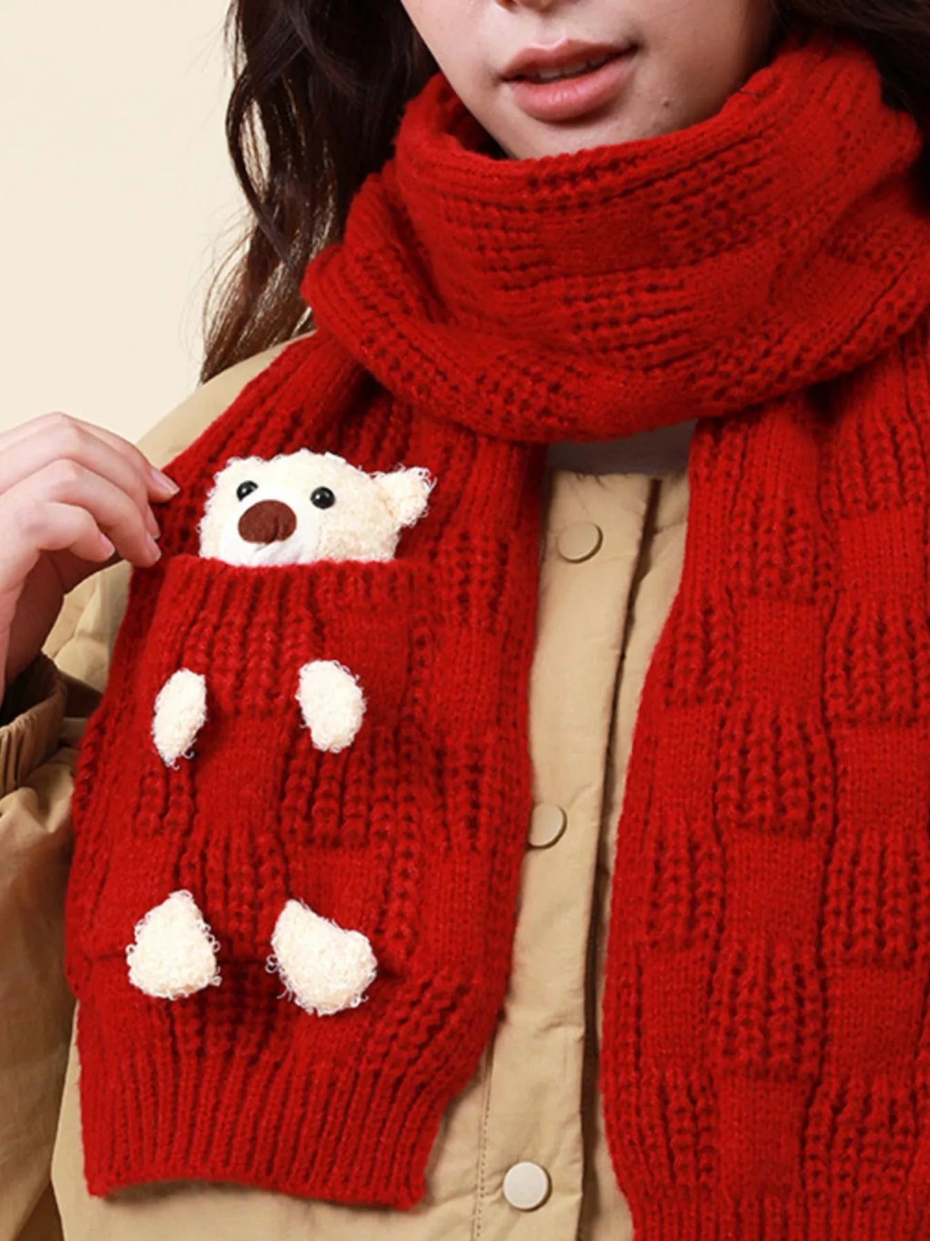 Knit winter scarf with teddy bear pocket detail worn over a jacket.