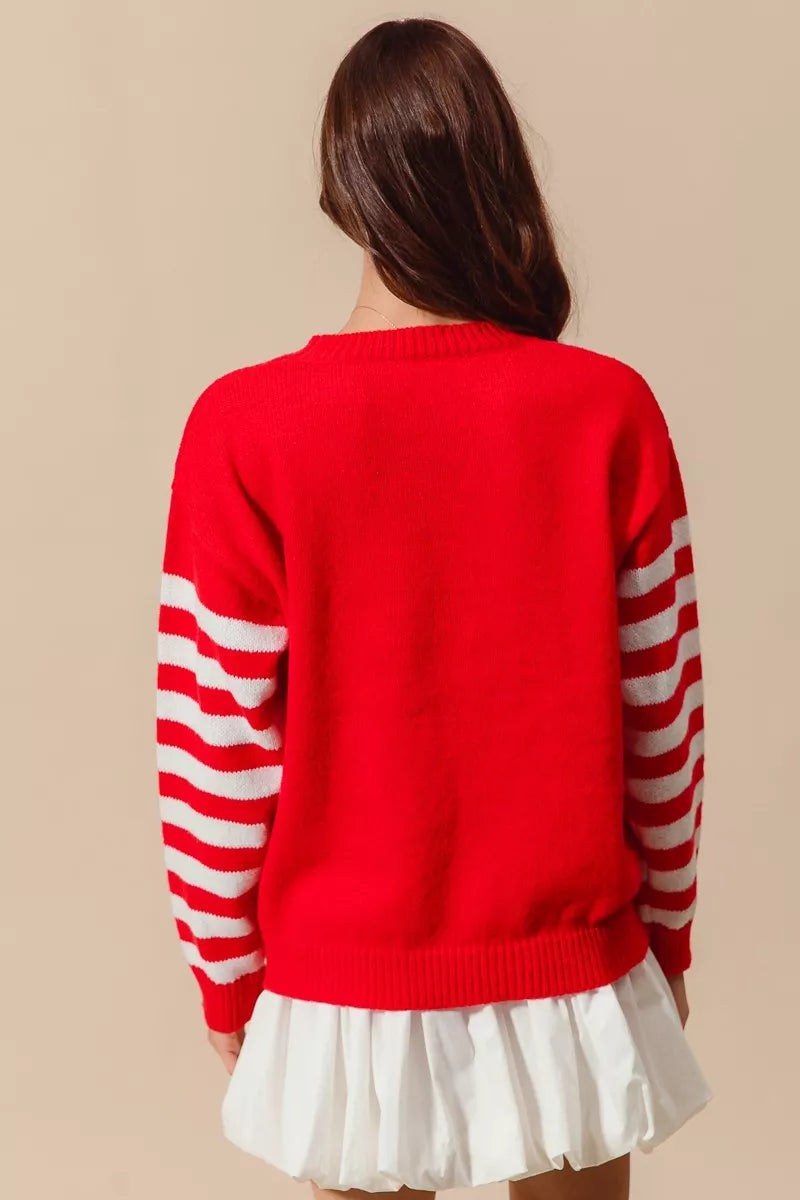 Woman wearing a red Christmas sweater with white striped sleeves and a crochet snowflake embellishment — festive knit from A Whimsical Affair.