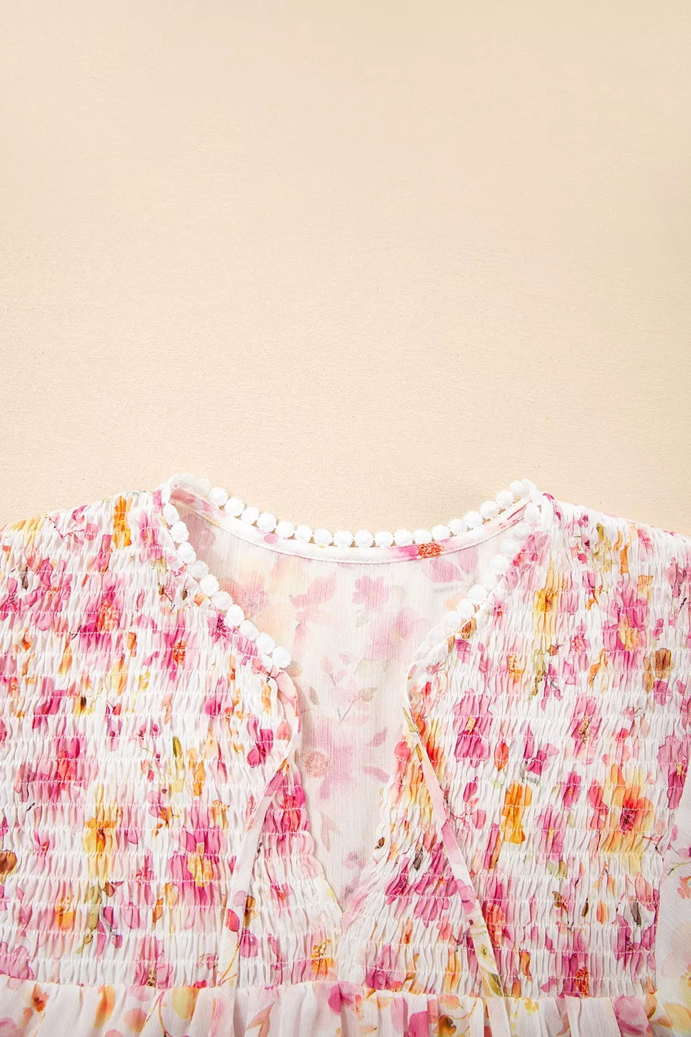 Pink floral smocked blouse with long sleeves and front tie detail
