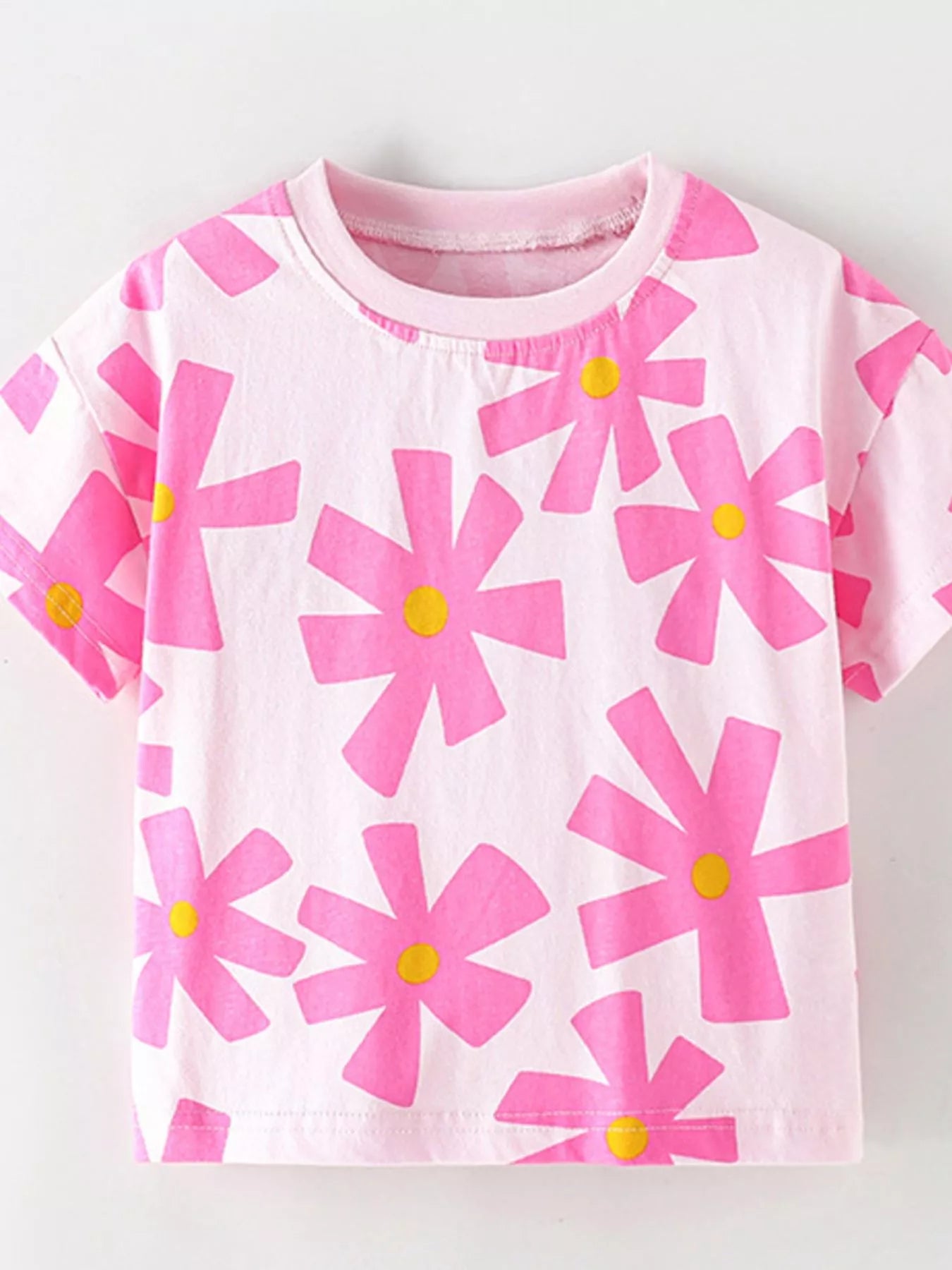 Girls pink short sleeve tee with oversized flower print, relaxed fit, and soft cotton-blend fabric styled with denim shorts.