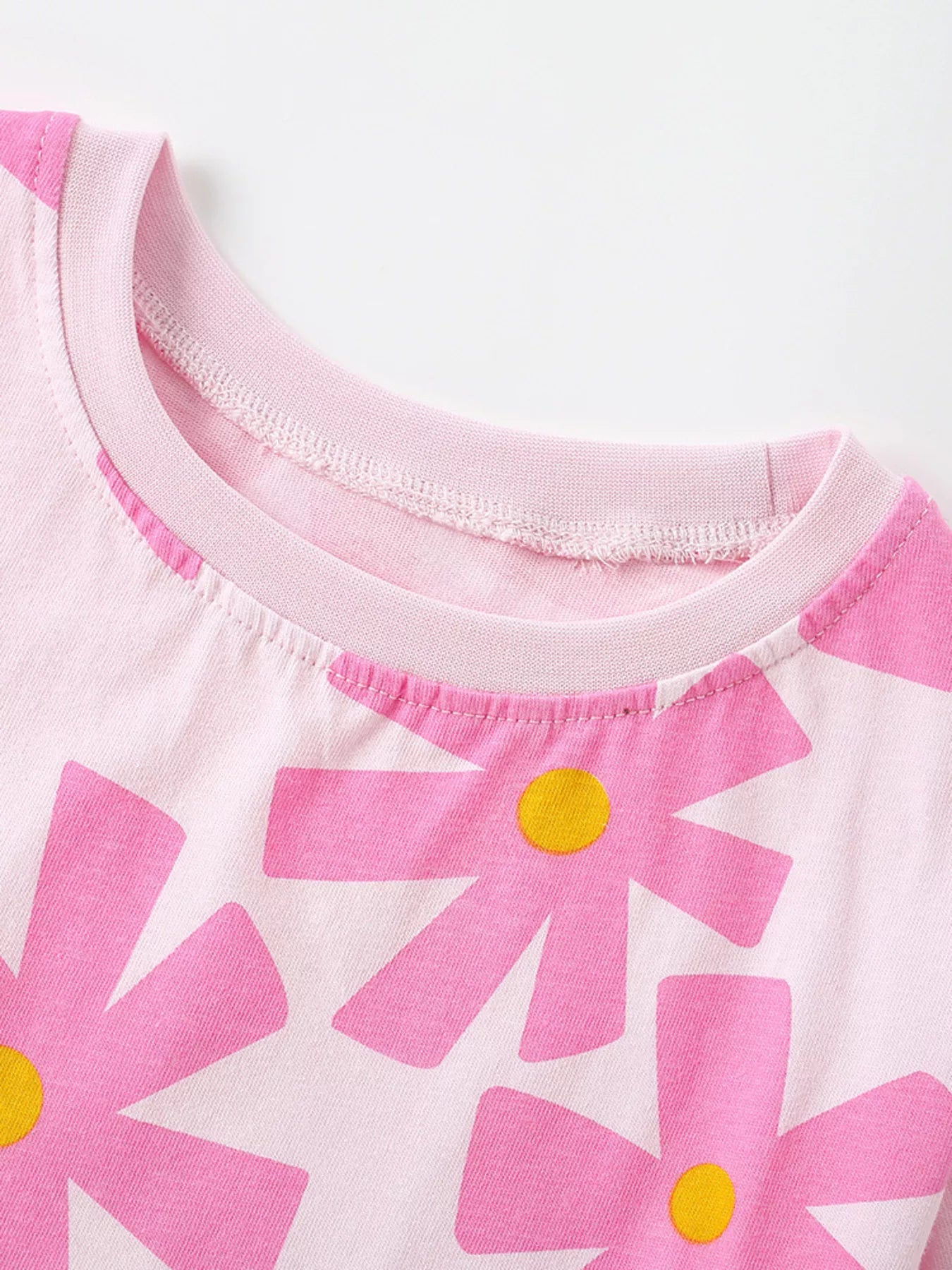 Girls pink short sleeve tee with oversized flower print, relaxed fit, and soft cotton-blend fabric styled with denim shorts.