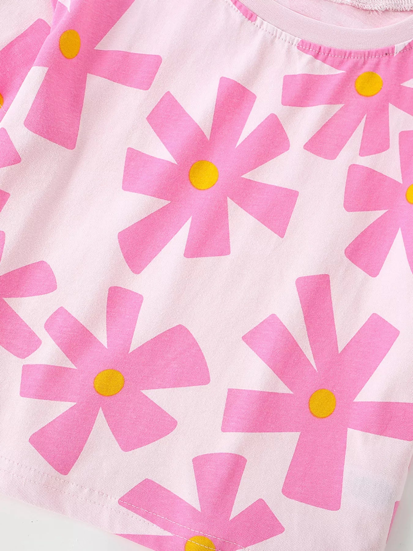 Girls pink short sleeve tee with oversized flower print, relaxed fit, and soft cotton-blend fabric styled with denim shorts.