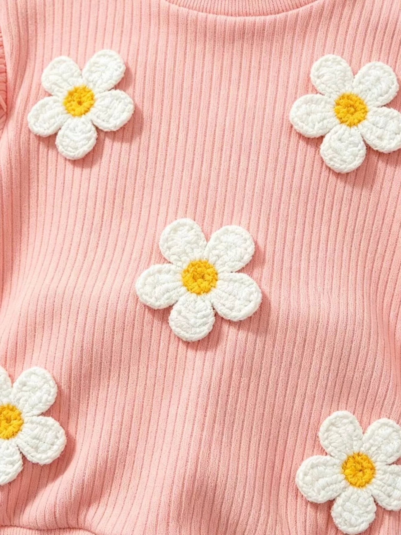 Children’s two-piece outfit with daisy appliqué details, ruffled shoulders, ribbed top, flared pants, and soft cotton-blend fabric.