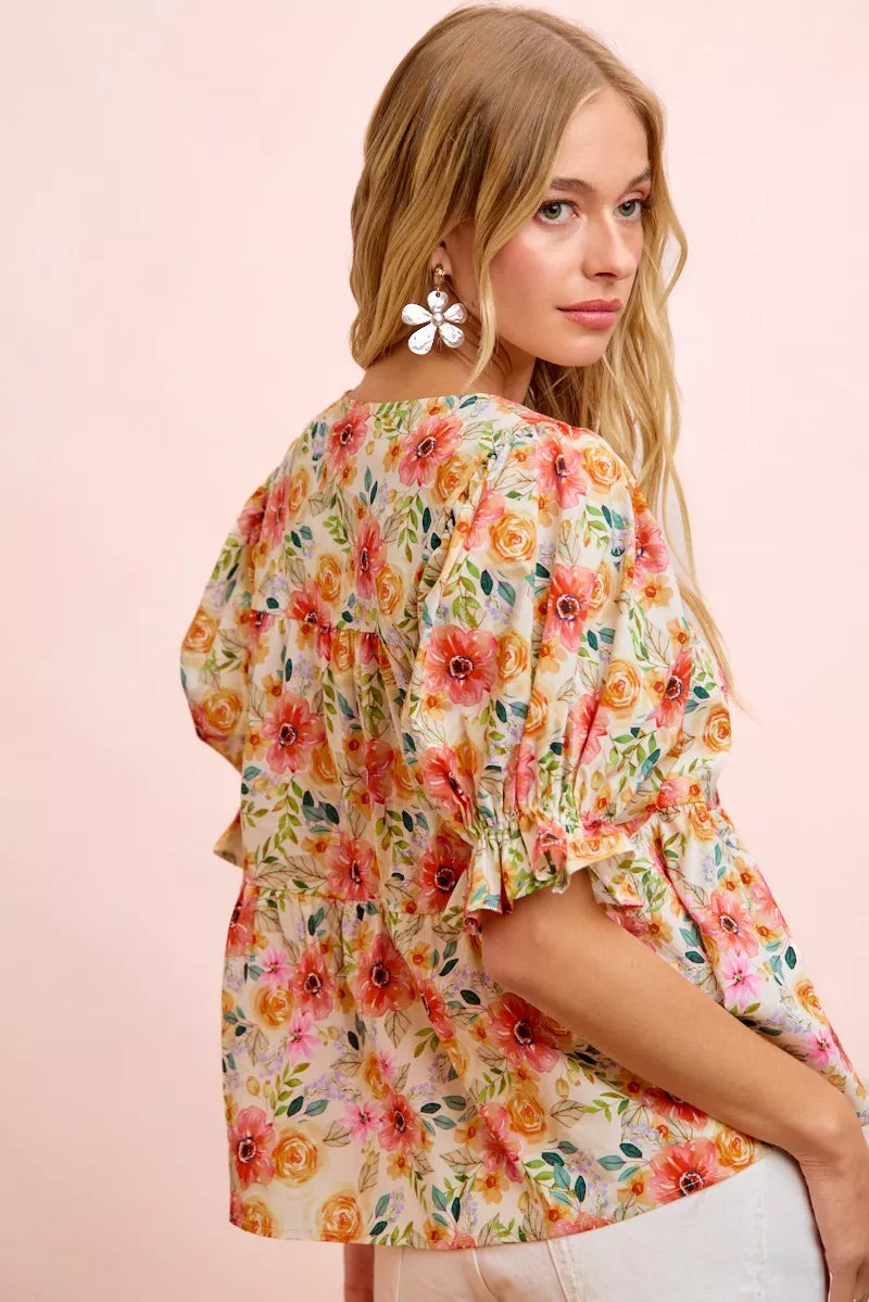 Floral cotton blouse with tie-front neckline, ruffled details, frill accents, puff sleeves, and soft romantic cottage style.
