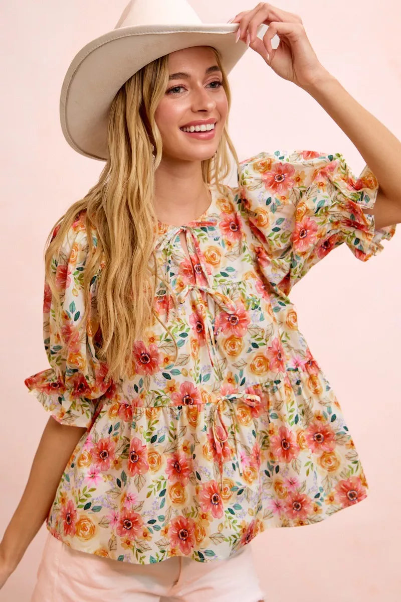 Floral cotton blouse with tie-front neckline, ruffled details, frill accents, puff sleeves, and soft romantic cottage style.