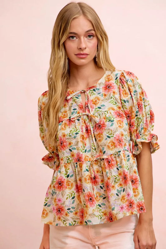 Floral cotton blouse with tie-front neckline, ruffled details, frill accents, puff sleeves, and soft romantic cottage style.