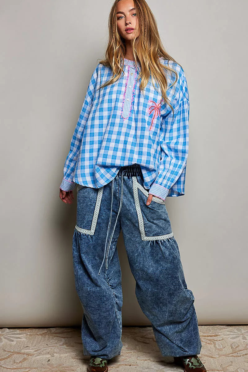 Blue and white gingham cotton blouse with buttoned neckline, lace detail, embroidered palm tree pocket, and relaxed fit.