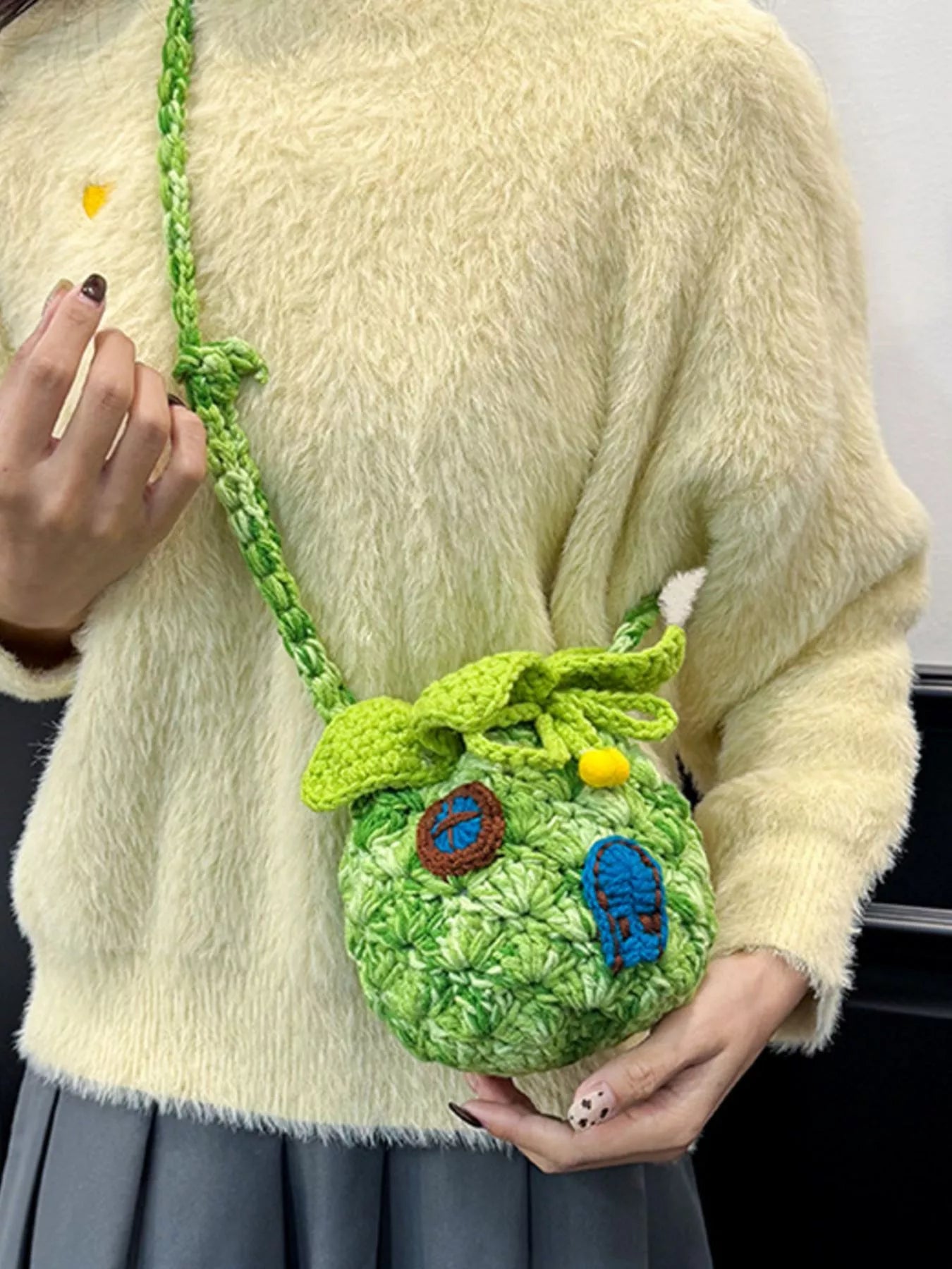 Pineapple-shaped knitted mini crossbody bag worn over a fuzzy sweater