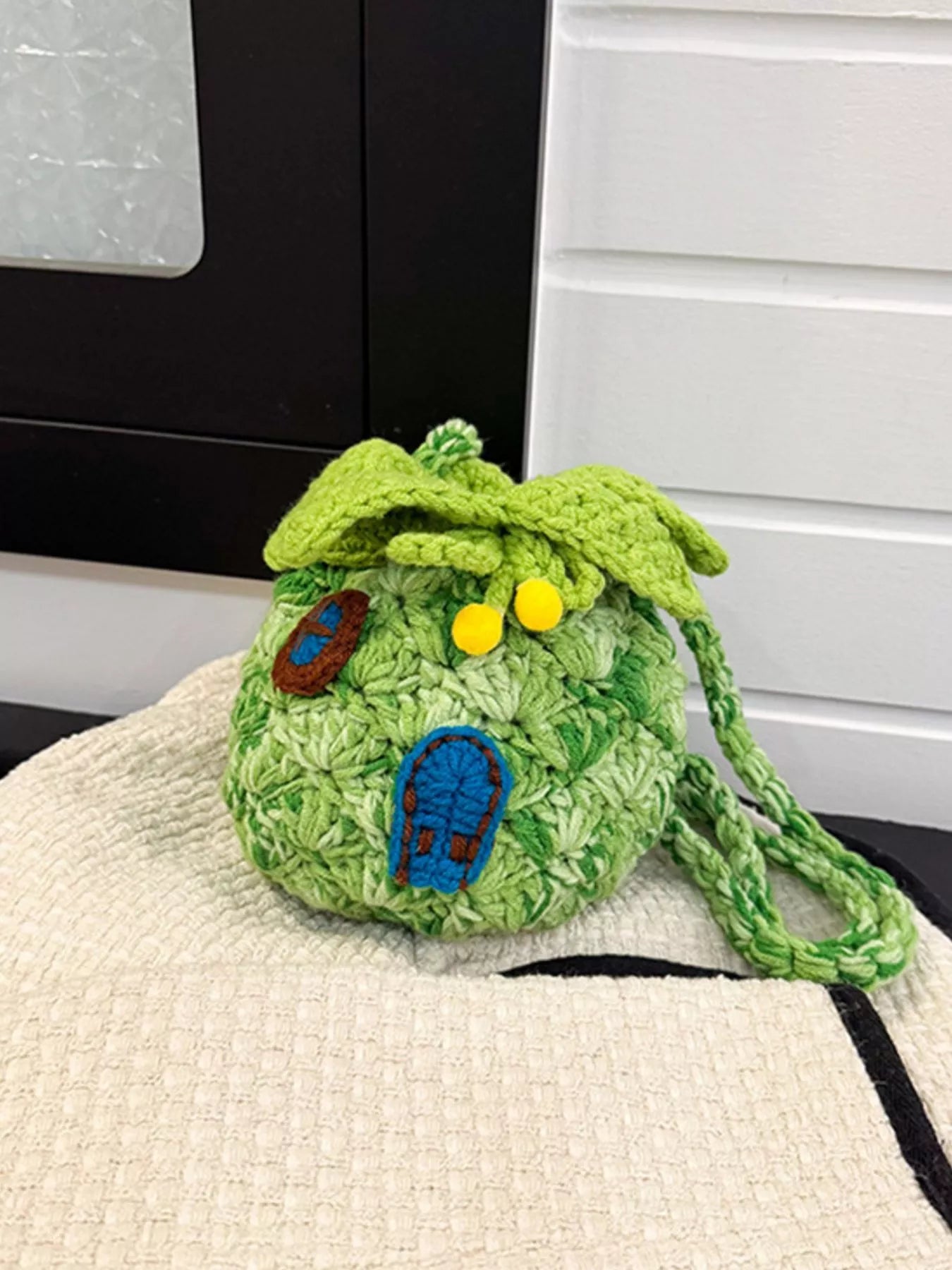 Pineapple-shaped knitted mini crossbody bag worn over a fuzzy sweater