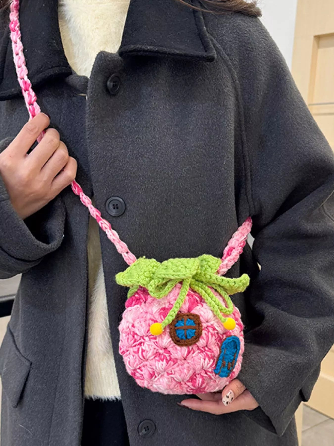 Pineapple-shaped knitted mini crossbody bag worn over a fuzzy sweater
