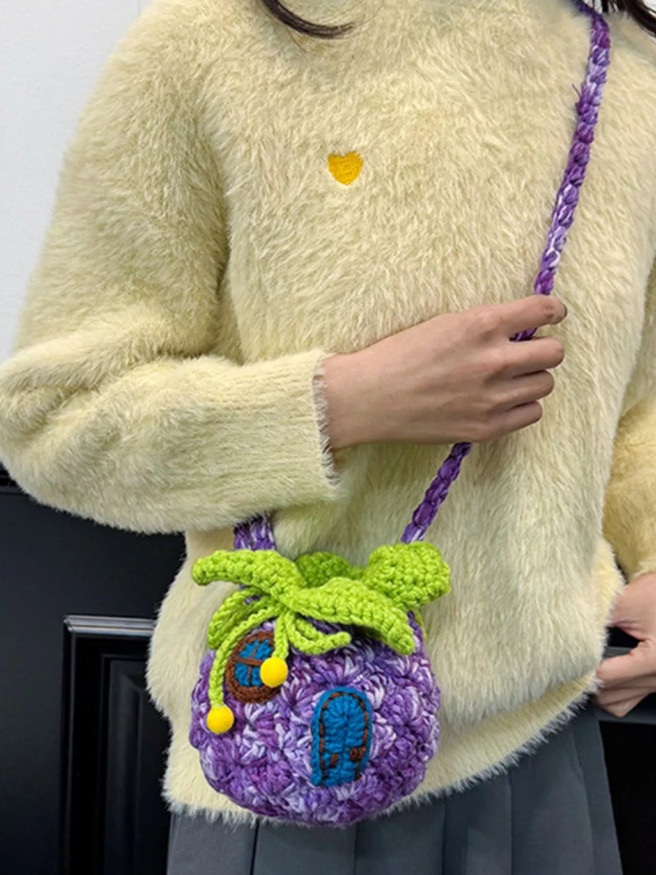 Pineapple-shaped knitted mini crossbody bag worn over a fuzzy sweater