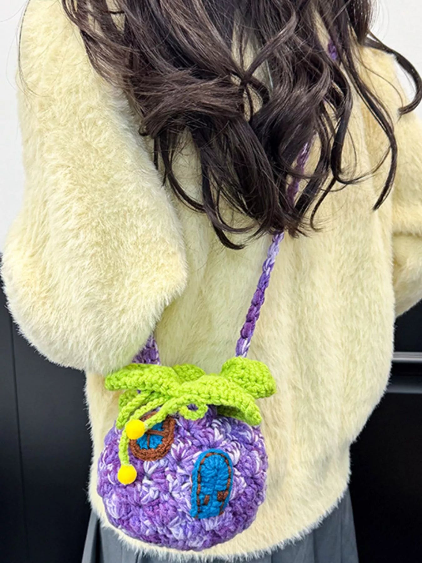 Pineapple-shaped knitted mini crossbody bag worn over a fuzzy sweater