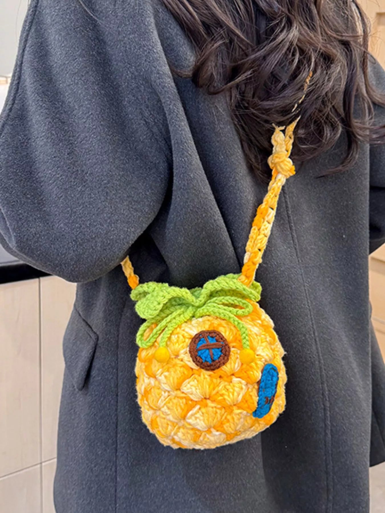 Pineapple-shaped knitted mini crossbody bag worn over a fuzzy sweater