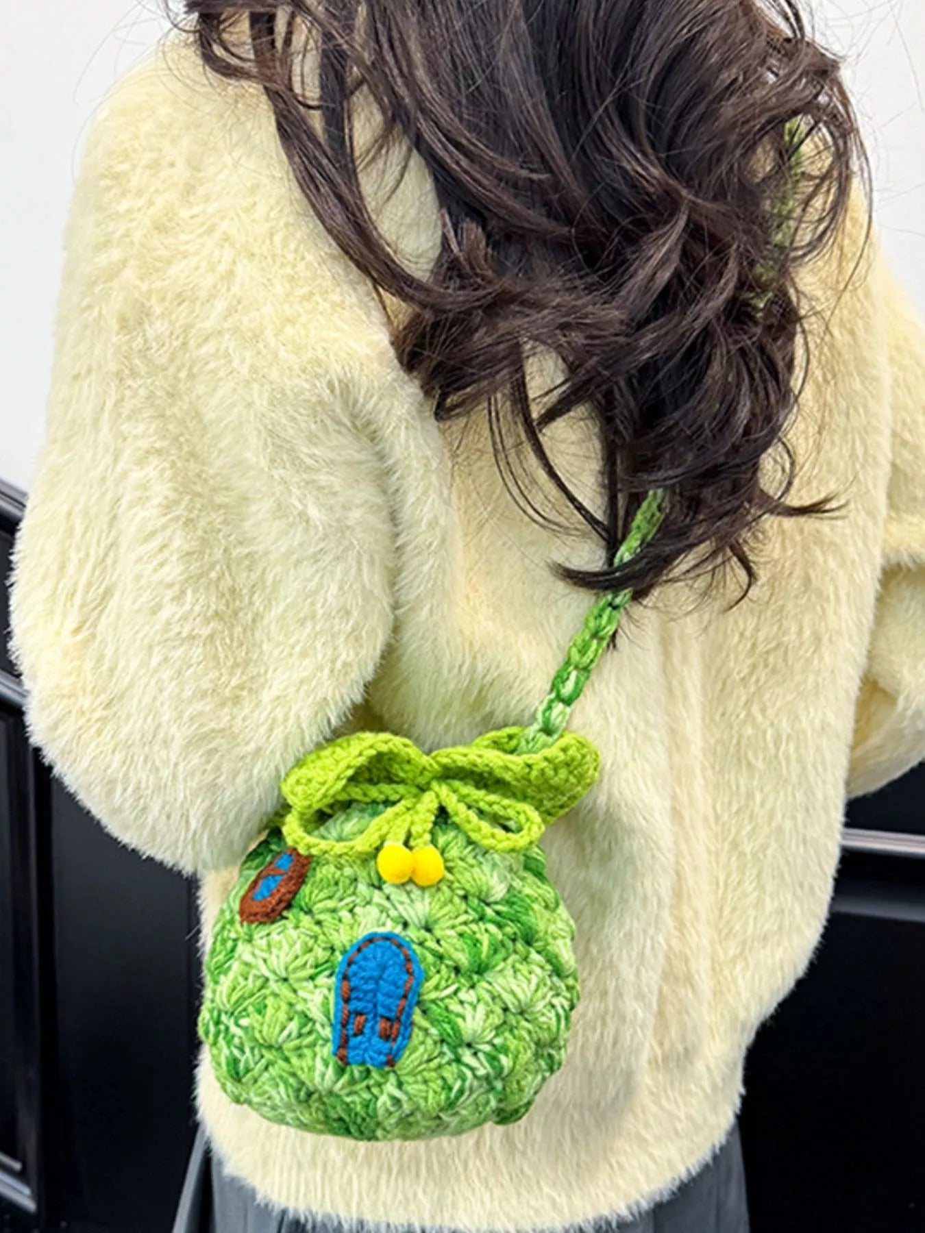 Pineapple-shaped knitted mini crossbody bag worn over a fuzzy sweater