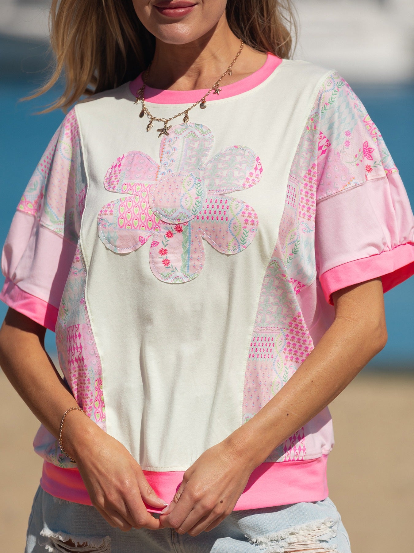 Woman wearing a pink patchwork floral short sleeve tee with bright contrast trim