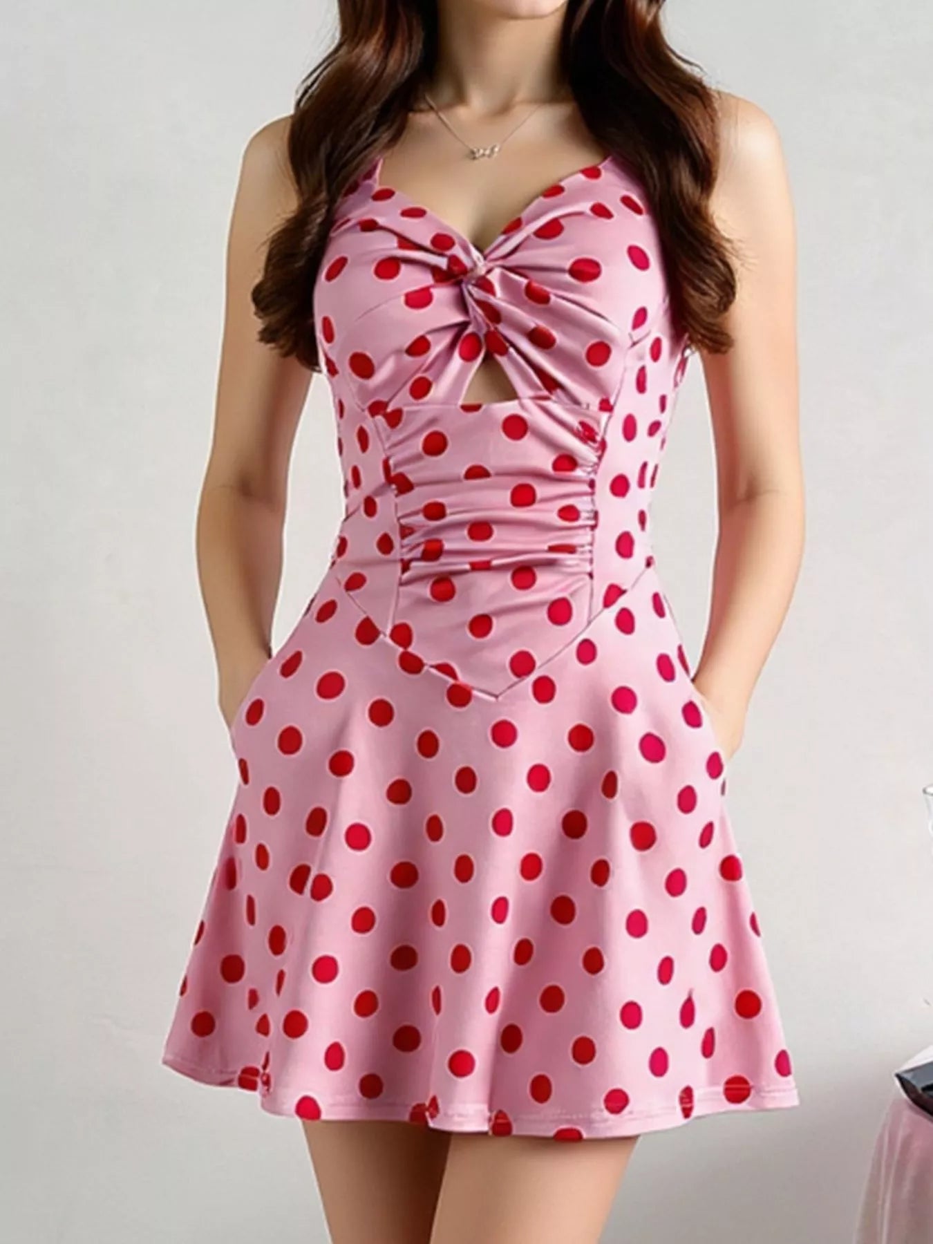 Pink halter mini dress with red polka dots, twisted front, ruched details, and flared skirt.