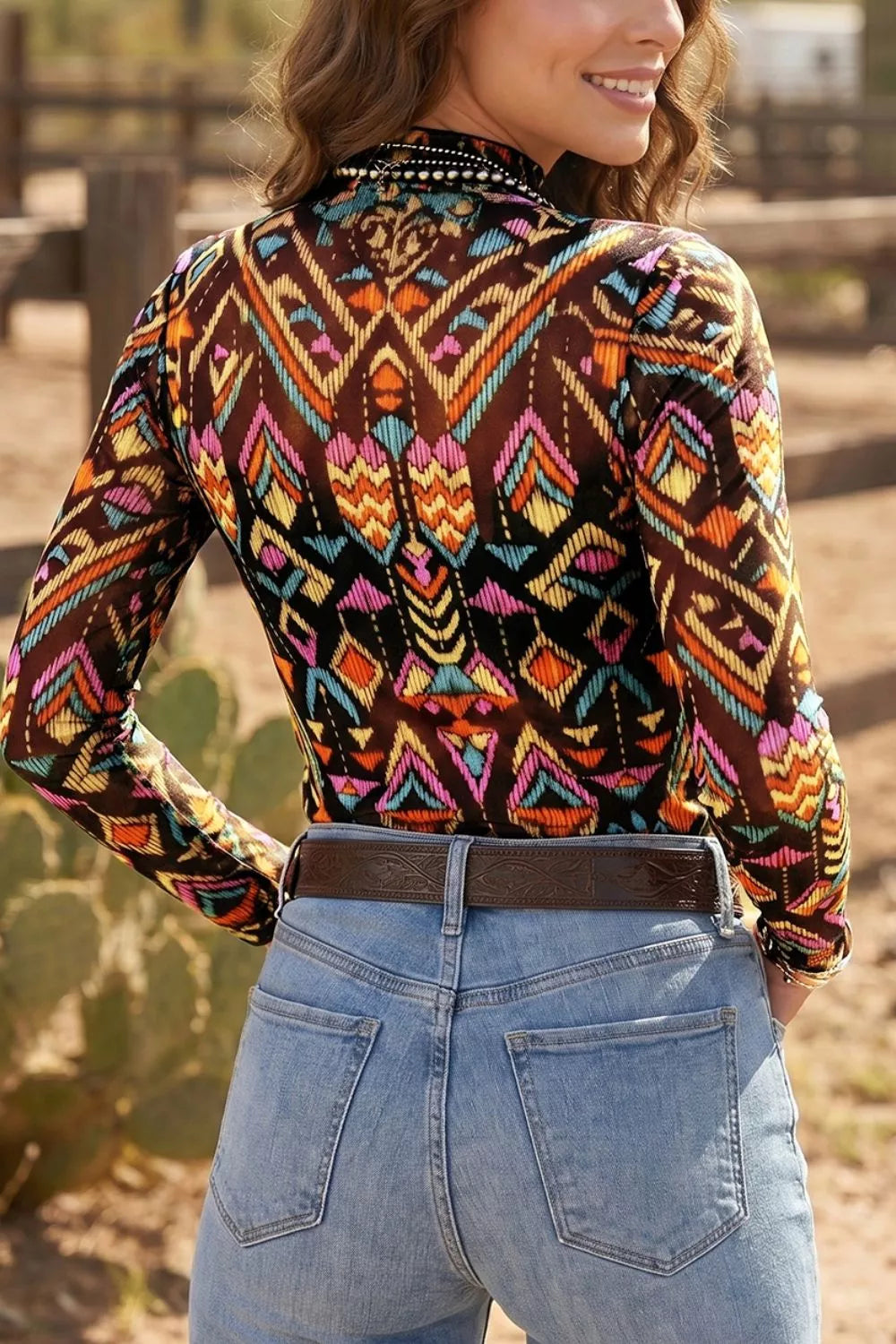 Colorful western-inspired mock neck mesh top with geometric print, long sleeves, and slightly stretchy fit styled with denim and turquoise jewelry.