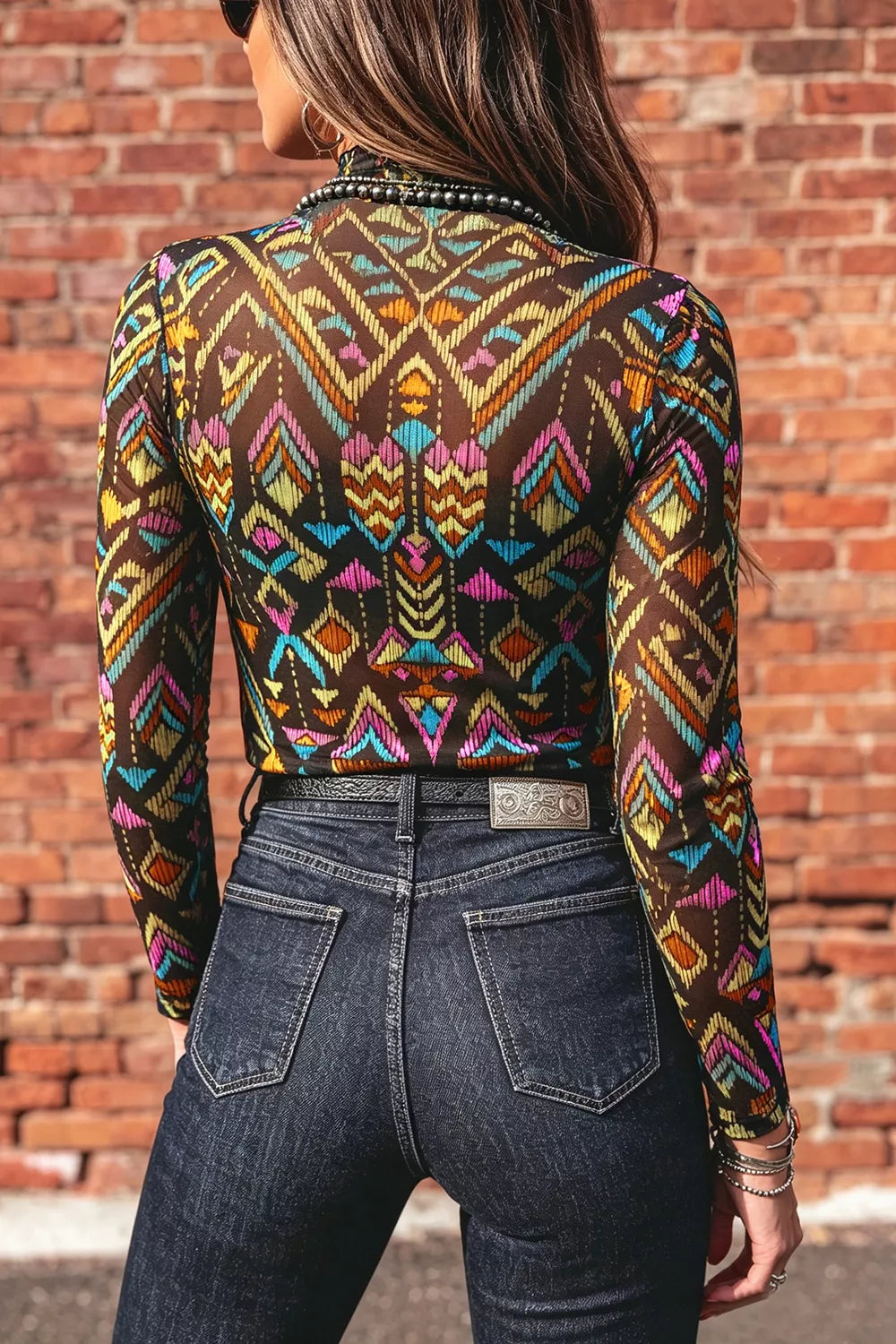 Colorful western-inspired mock neck mesh top with geometric print, long sleeves, and slightly stretchy fit styled with denim and turquoise jewelry.