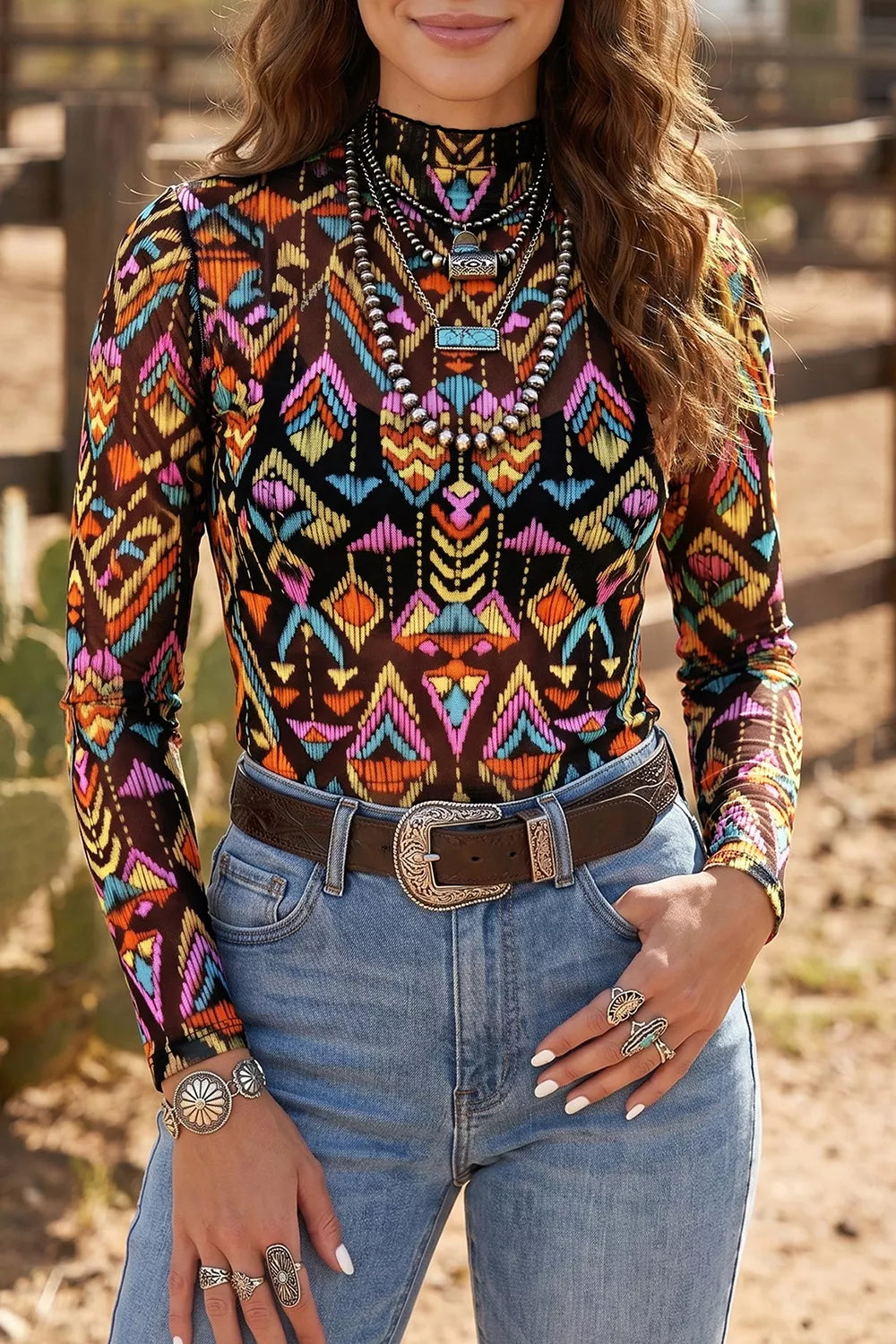 Colorful western-inspired mock neck mesh top with geometric print, long sleeves, and slightly stretchy fit styled with denim and turquoise jewelry.
