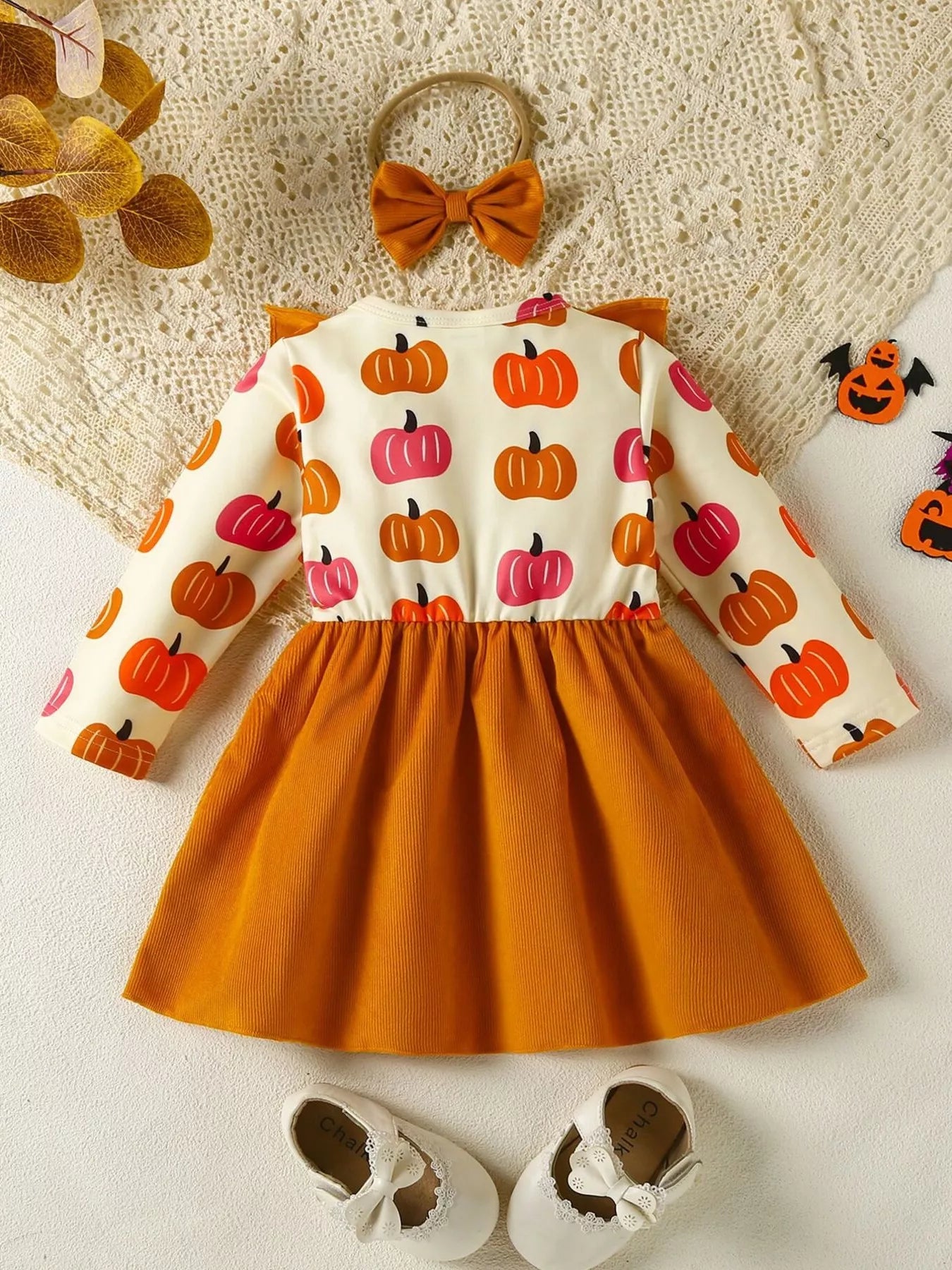 Baby girl pumpkin-print long-sleeve ruffle dress with bow headband and mustard corduroy skirt, styled for fall.