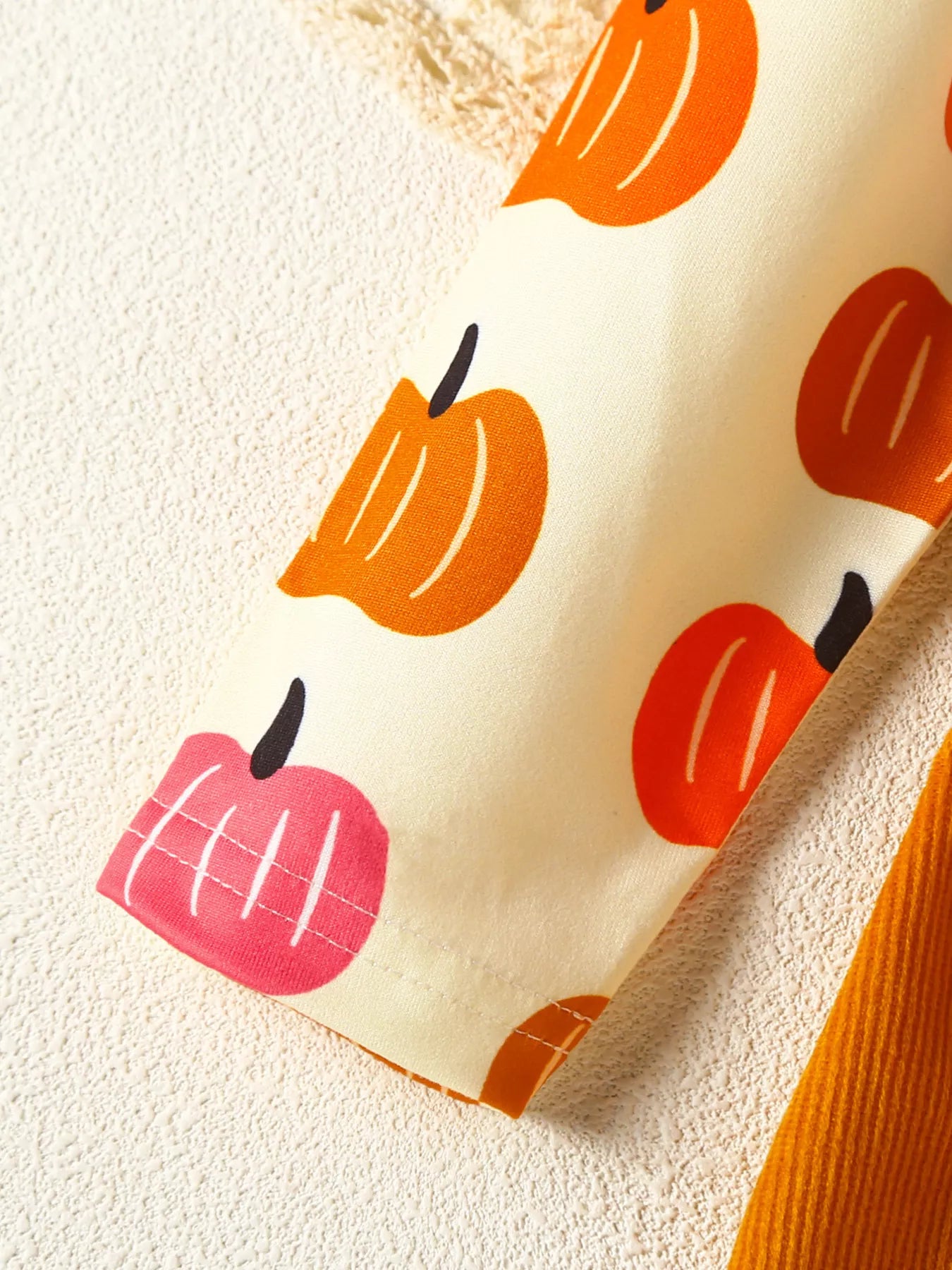 Baby girl pumpkin-print long-sleeve ruffle dress with bow headband and mustard corduroy skirt, styled for fall.