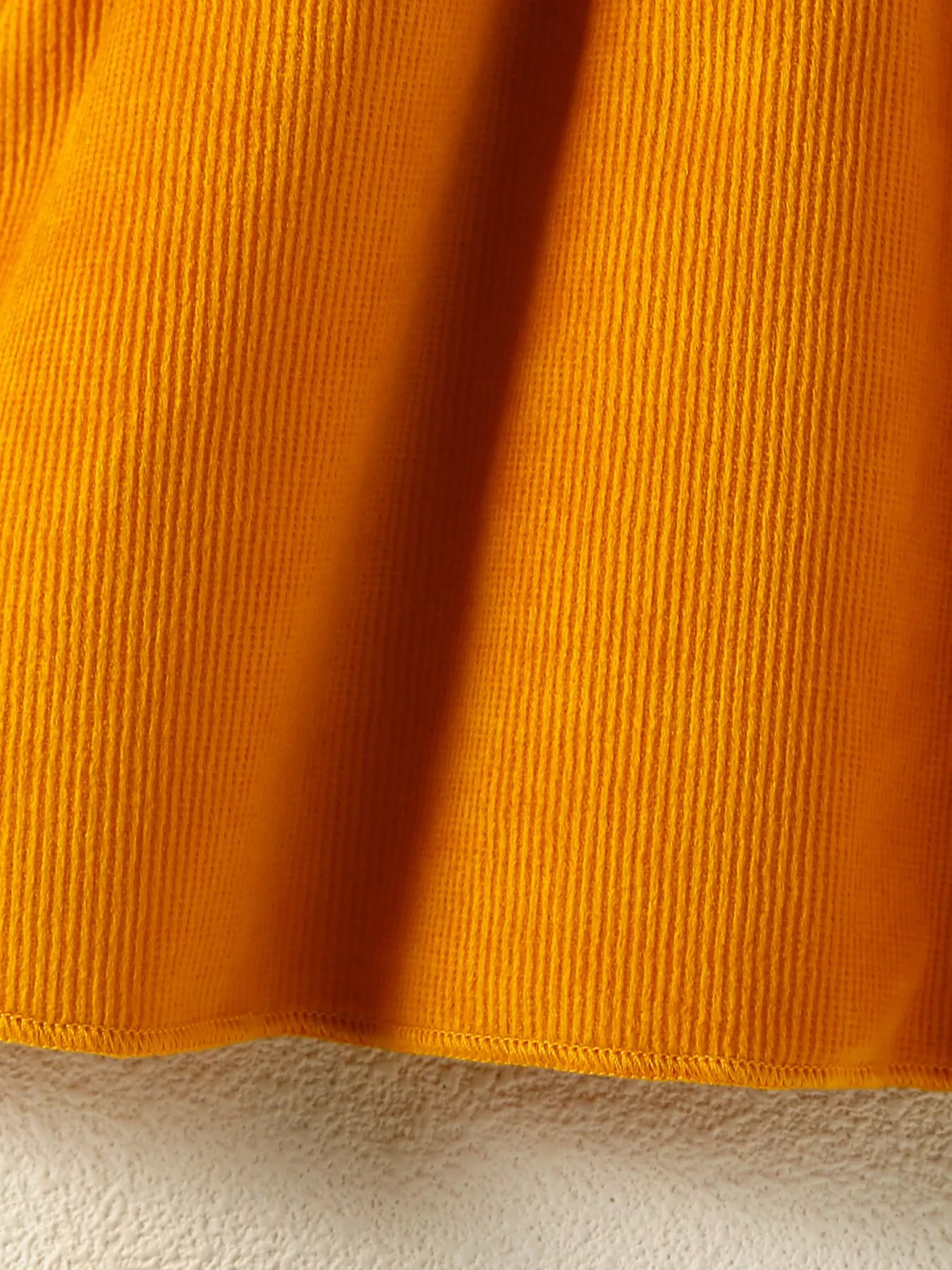 Baby girl pumpkin-print long-sleeve ruffle dress with bow headband and mustard corduroy skirt, styled for fall.