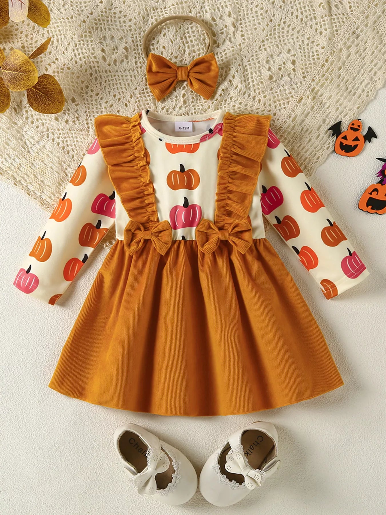 Baby girl pumpkin-print long-sleeve ruffle dress with bow headband and mustard corduroy skirt, styled for fall.
