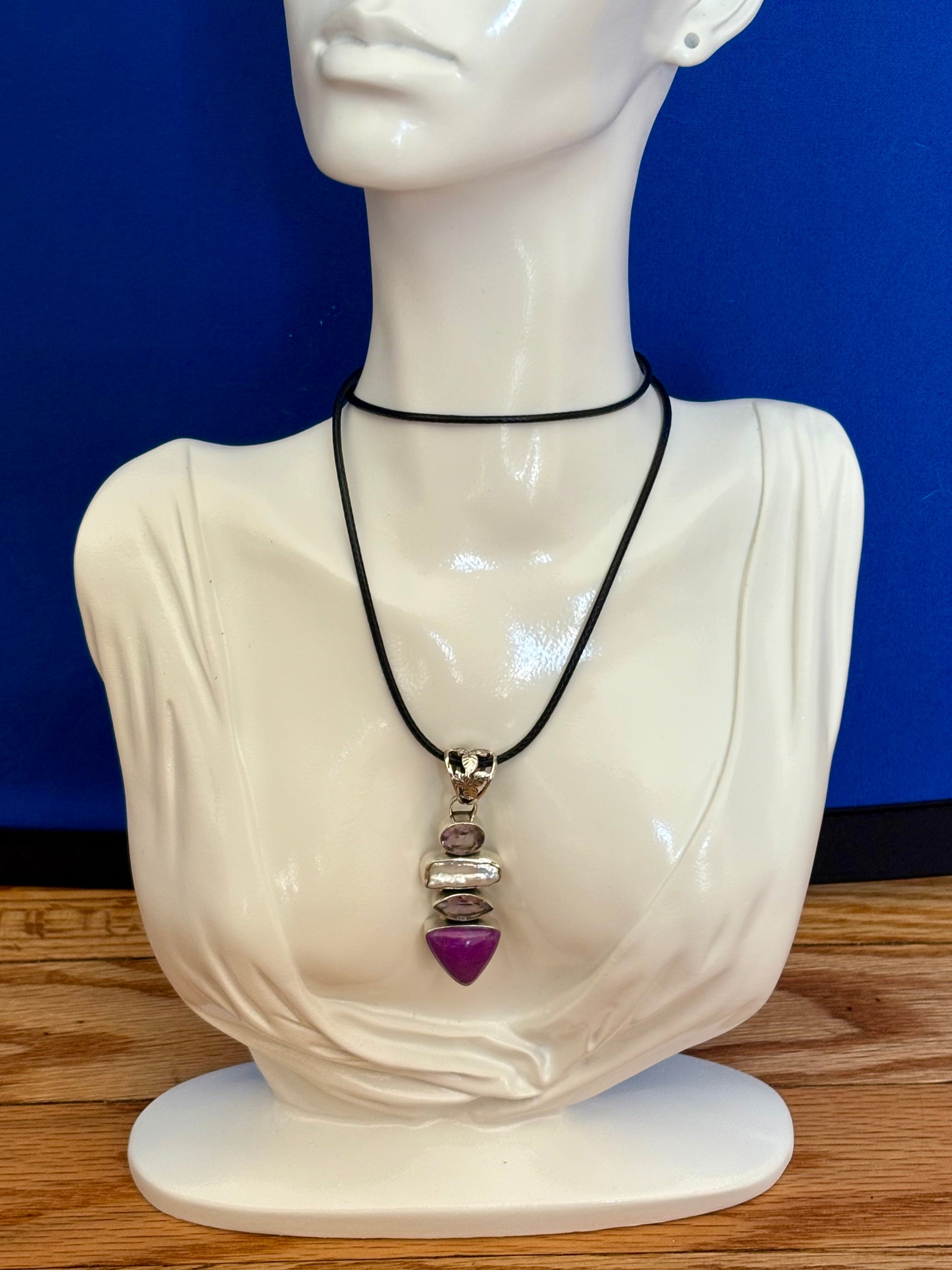 Mannequin bust wearing a necklace with a purple heart pendant against a blue background