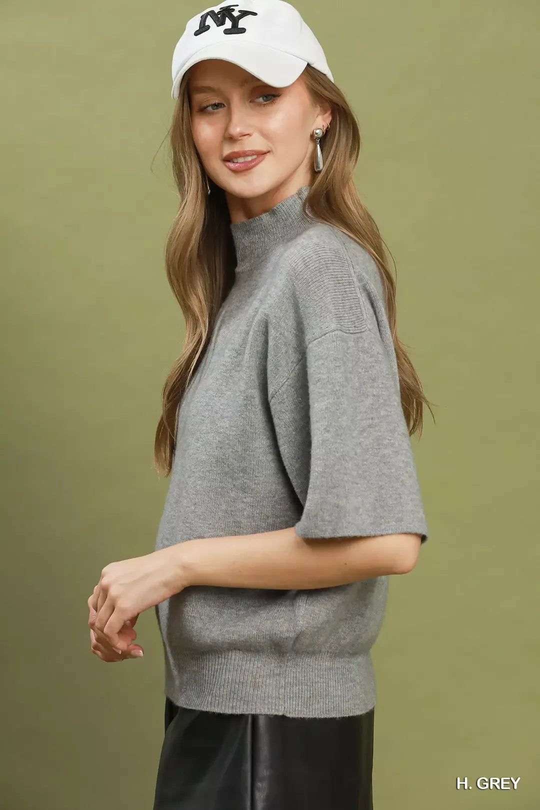 Short sleeve mock neck sweater top with ribbed trim, soft knit fabric, and slightly stretchy fit styled with faux leather shorts.