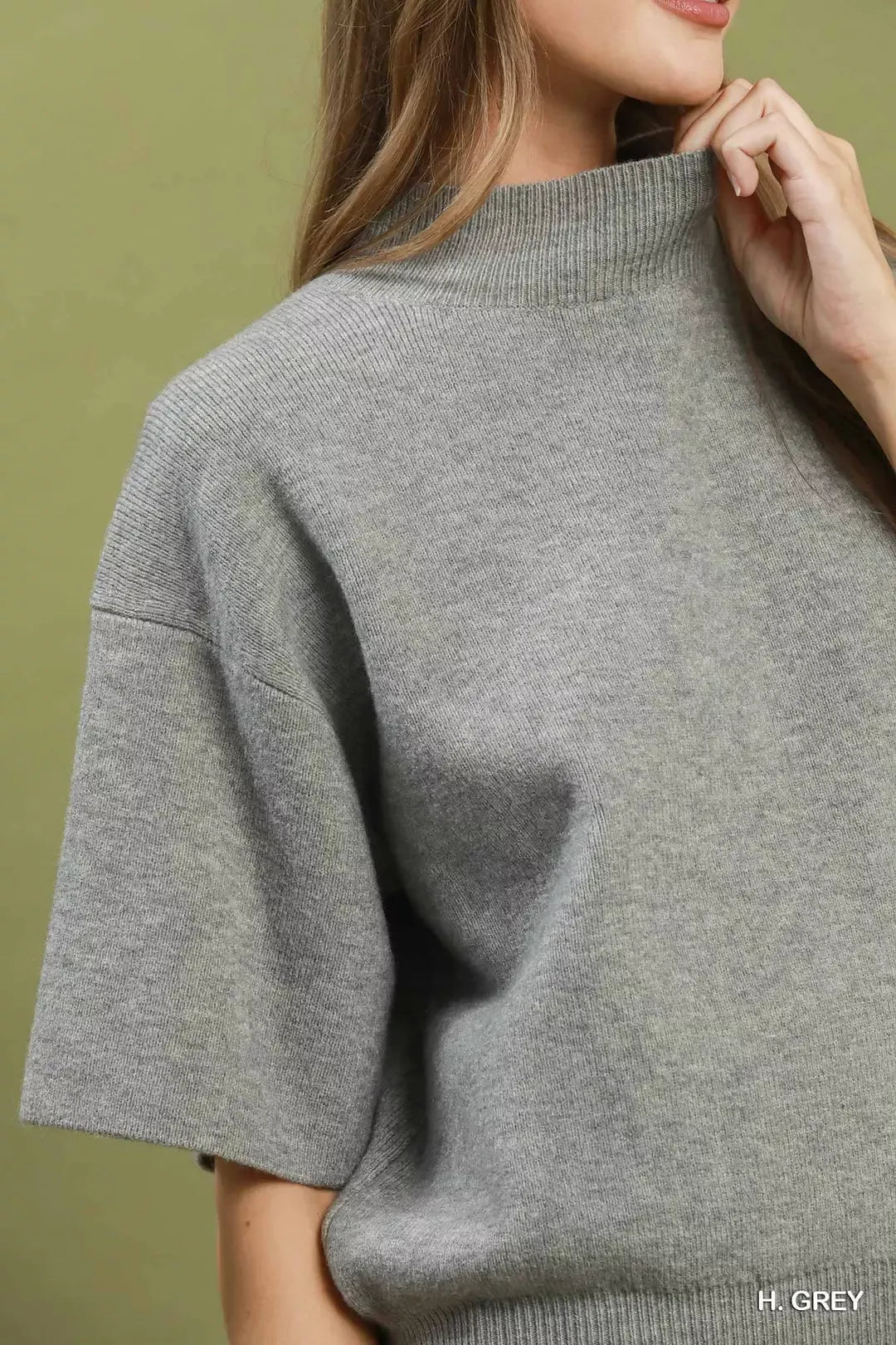 Short sleeve mock neck sweater top with ribbed trim, soft knit fabric, and slightly stretchy fit styled with faux leather shorts.
