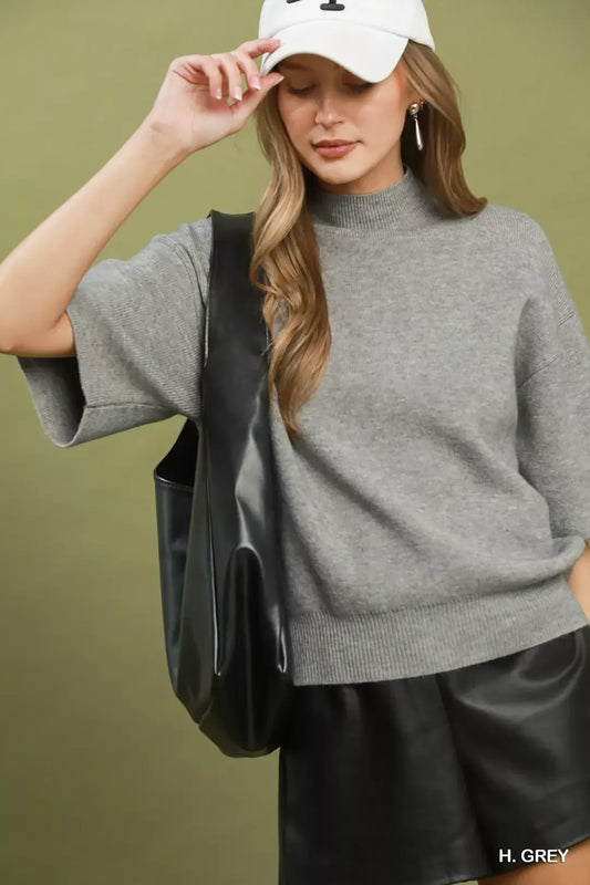 Short sleeve mock neck sweater top with ribbed trim, soft knit fabric, and slightly stretchy fit styled with faux leather shorts.