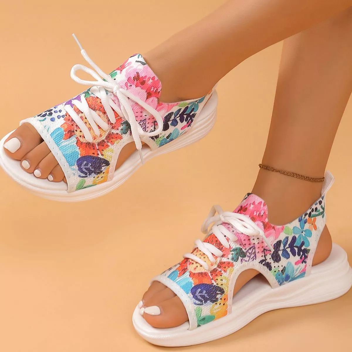 Colorful tie-dye mesh flat sandals with white laces, cutout sides, open toe design, and white rubber sole.