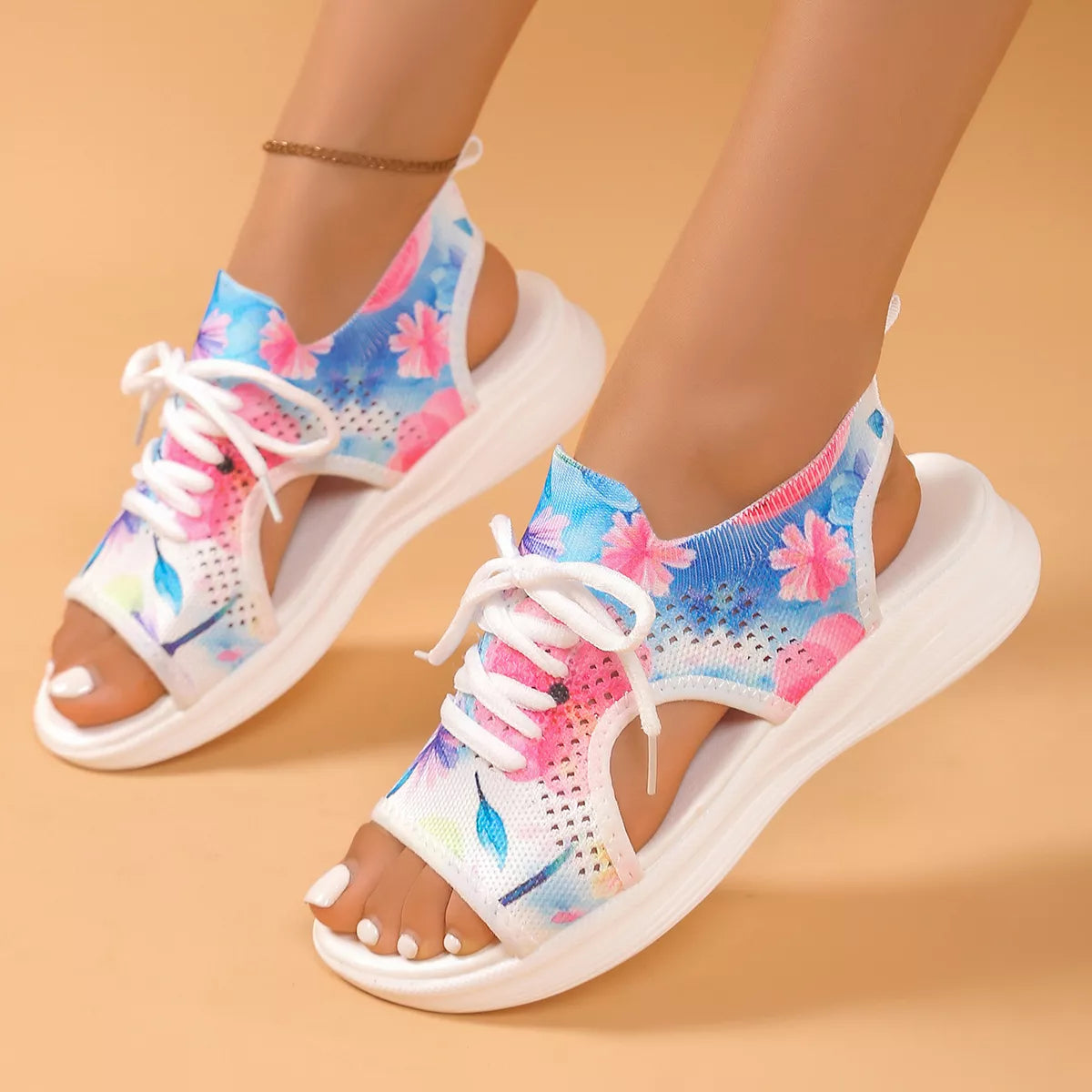 Colorful tie-dye mesh flat sandals with white laces, cutout sides, open toe design, and white rubber sole.