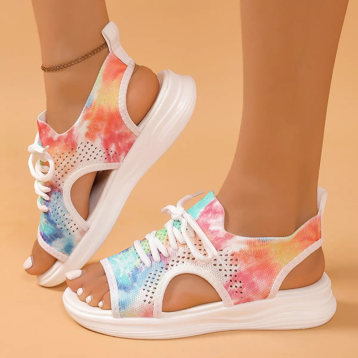 Colorful tie-dye mesh flat sandals with white laces, cutout sides, open toe design, and white rubber sole.