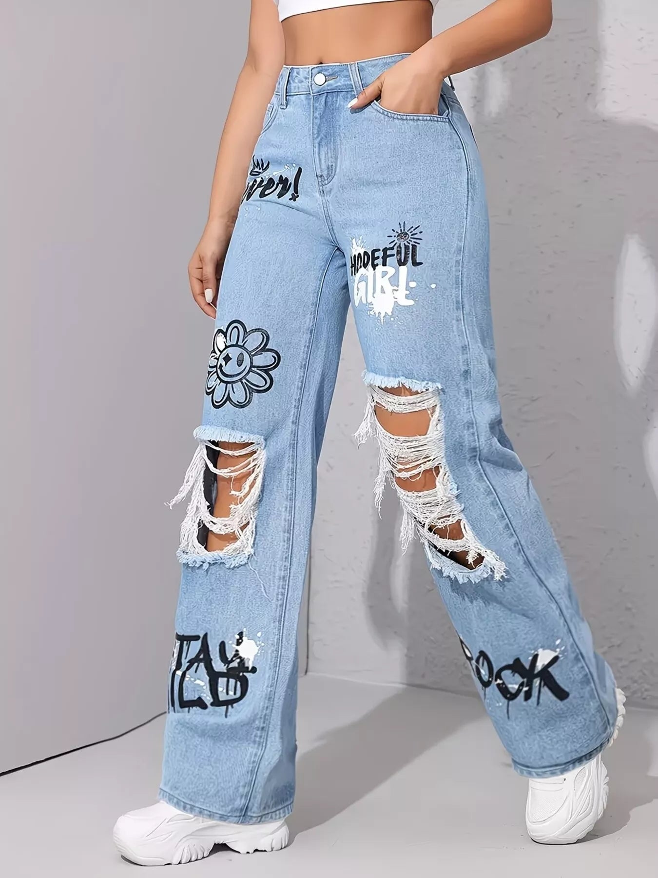 Light wash wide-leg jeans with distressed cutouts, raw hem details, seam accents, and black graphic print designs.