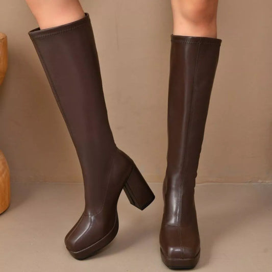 Woman wearing brown knee-high platform boots with a high heel and smooth PU leather finish