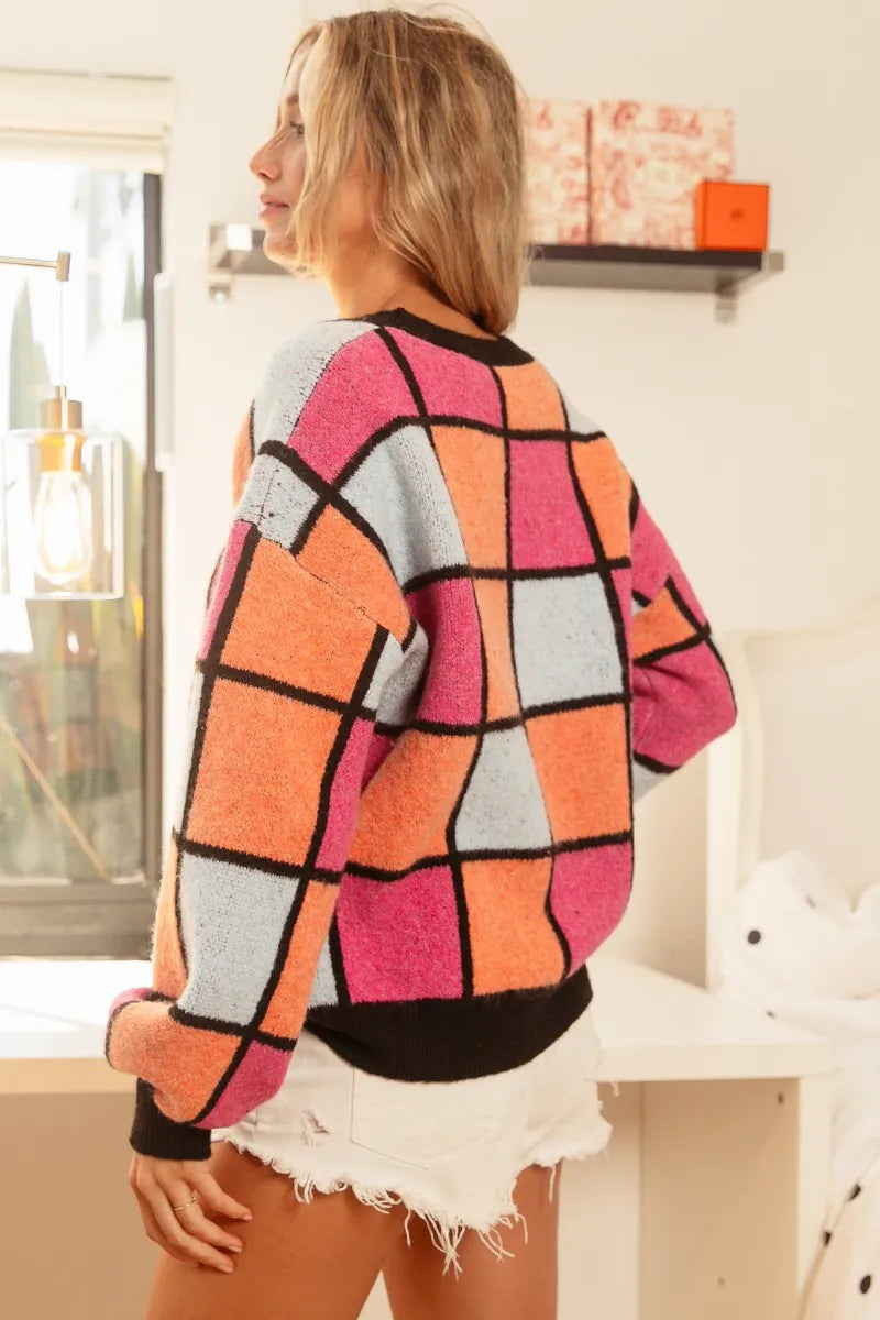 Colorful oversized sweater with pink, orange, and blue checker pattern outlined in black.